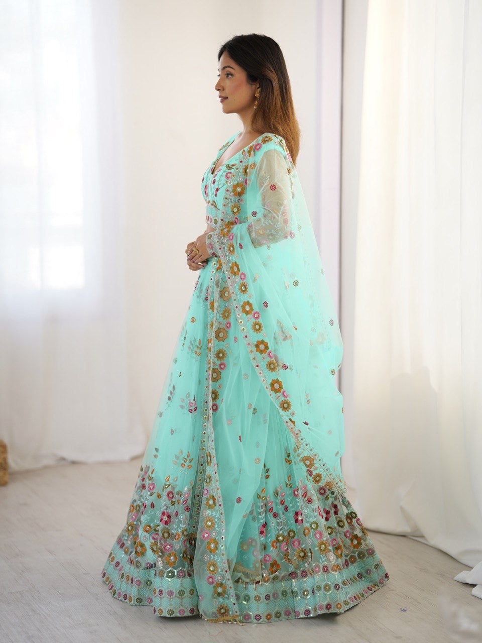 Woman wearing a light blue embroidered saree with a white blouse against a white background