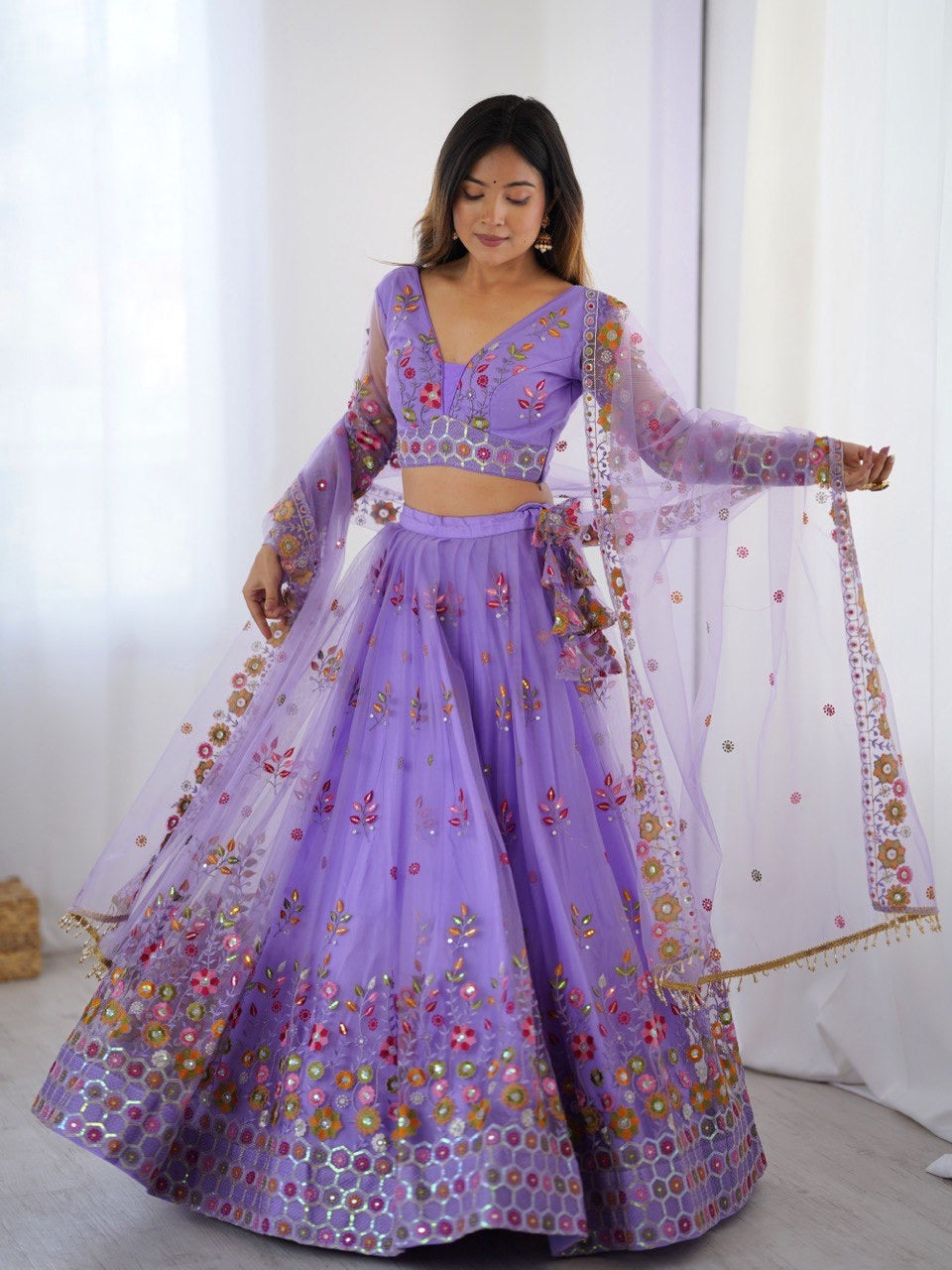 Woman wearing a purple embroidered traditional outfit with a white background