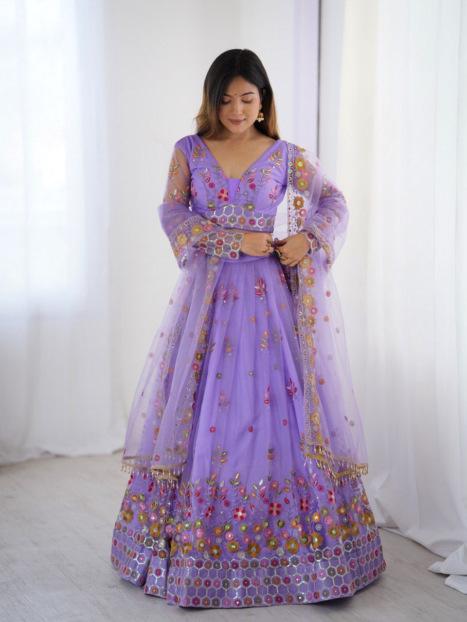 Woman wearing a purple embroidered traditional outfit with a white background