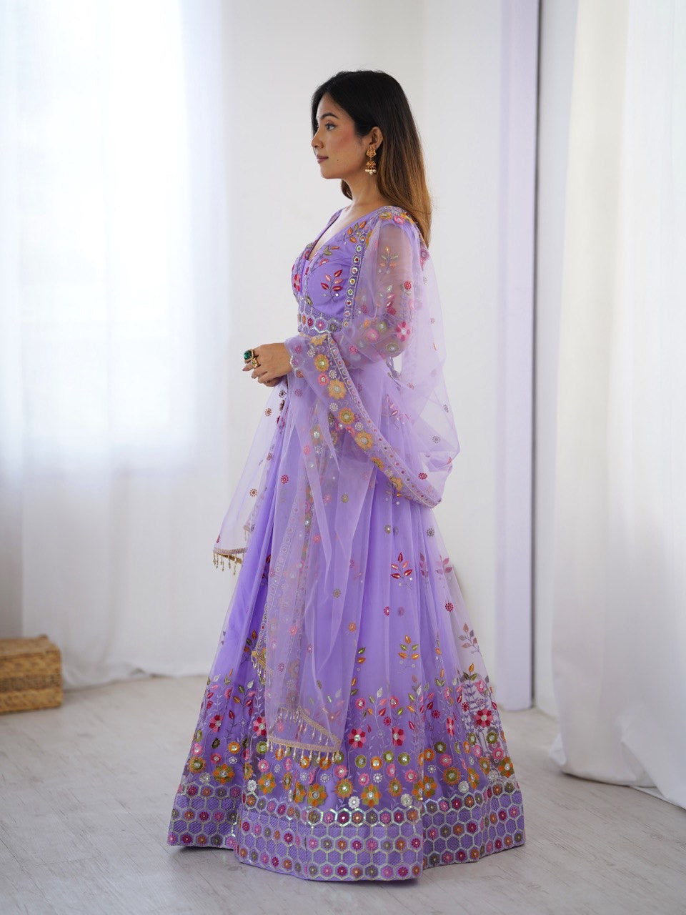 Woman wearing a purple embroidered traditional outfit in a minimalistic setting