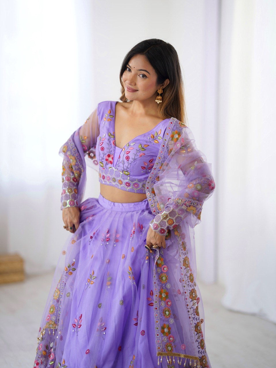 Woman wearing a purple embroidered outfit with a white background