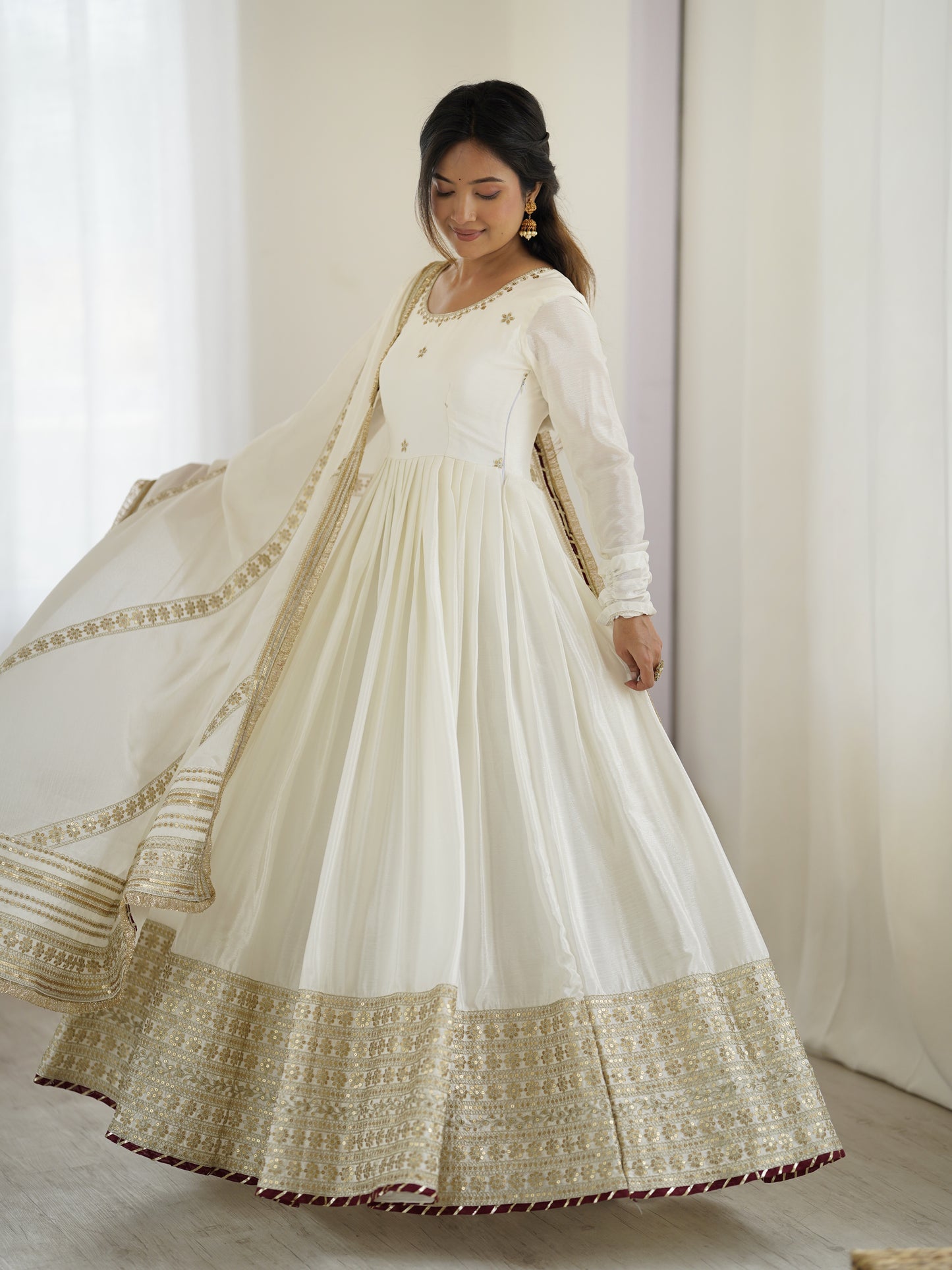 Woman wearing a white and gold traditional outfit with a plain background