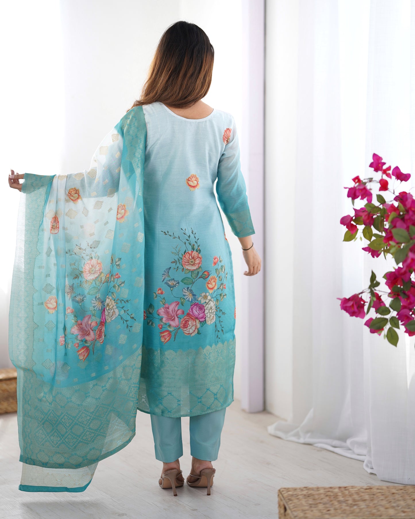 Woman wearing a light blue embroidered outfit with a matching dupatta, standing against a white background.