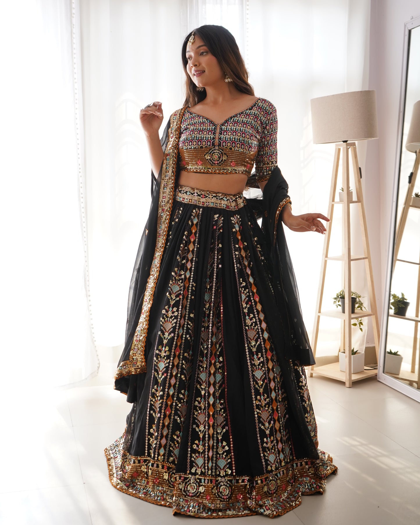 Woman in a traditional black and gold embroidered outfit standing in a bright room.