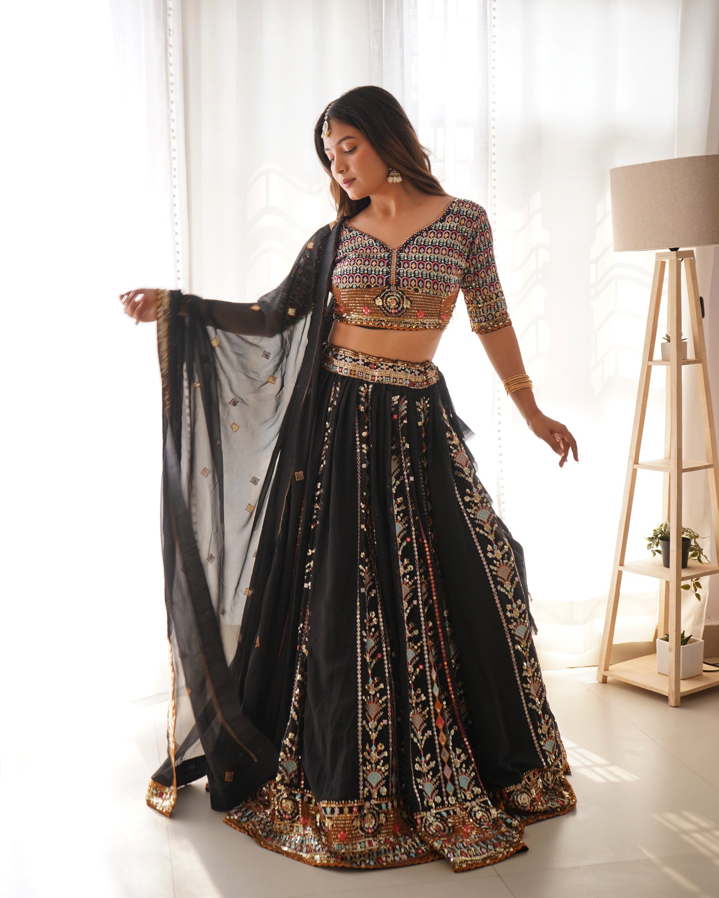 Woman in a traditional black and patterned outfit standing in a bright room.