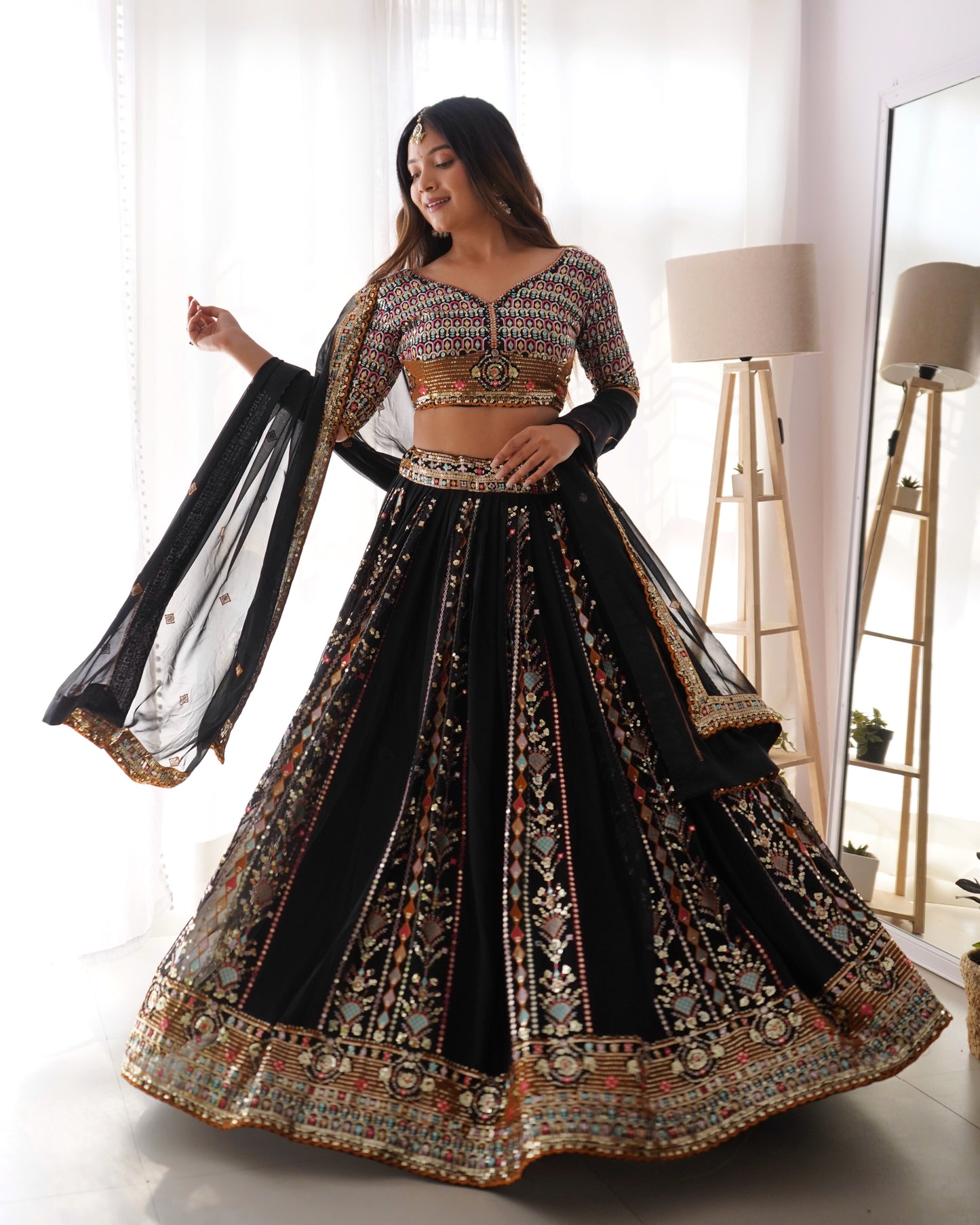 Woman wearing a black and gold embroidered traditional outfit in a bright room.