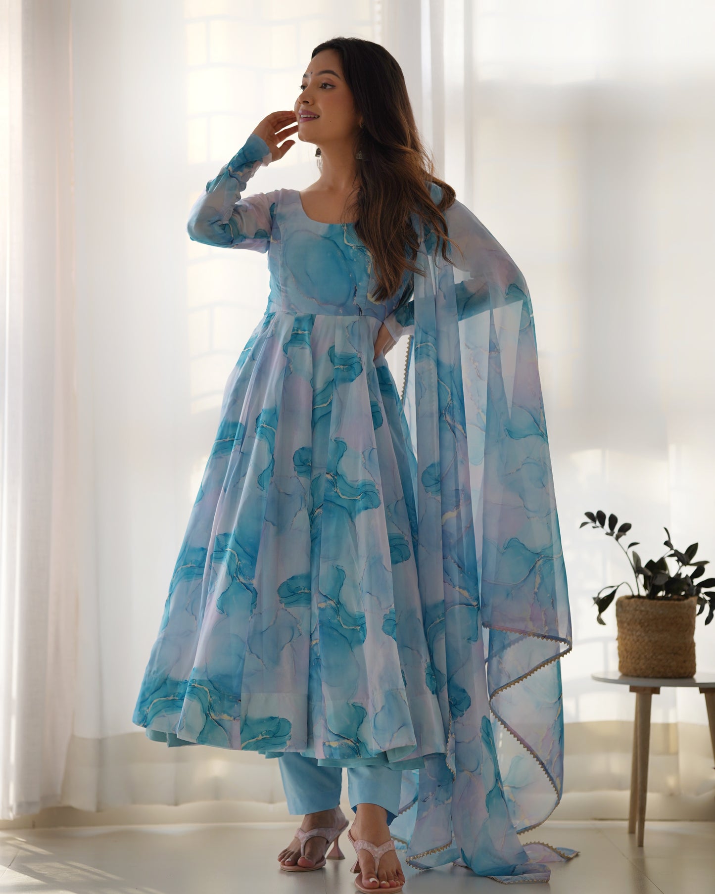 Woman wearing a blue floral dress with a matching dupatta in a bright room.