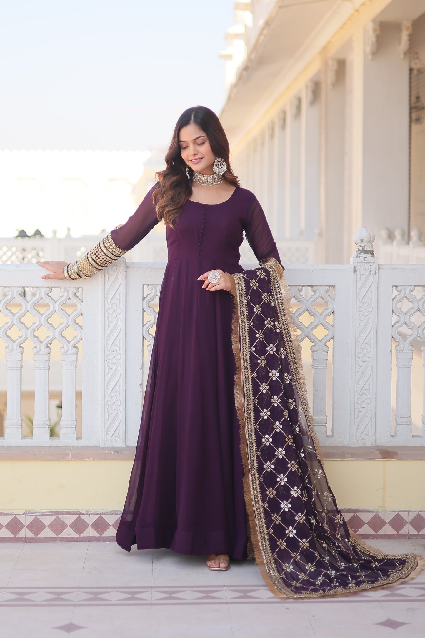Woman in a long purple dress with gold accents standing on a staircase.