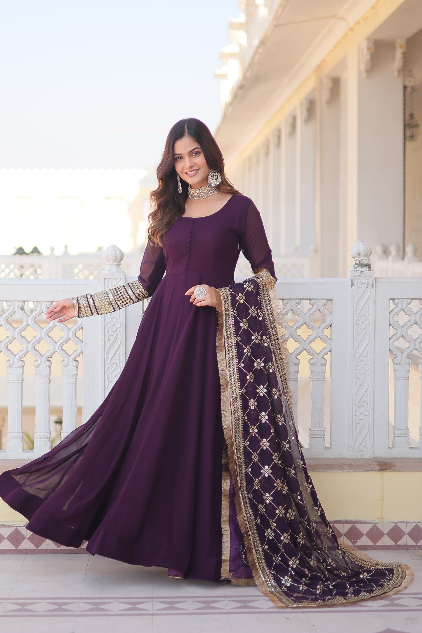 Woman in a purple traditional outfit with a long skirt standing on a staircase.