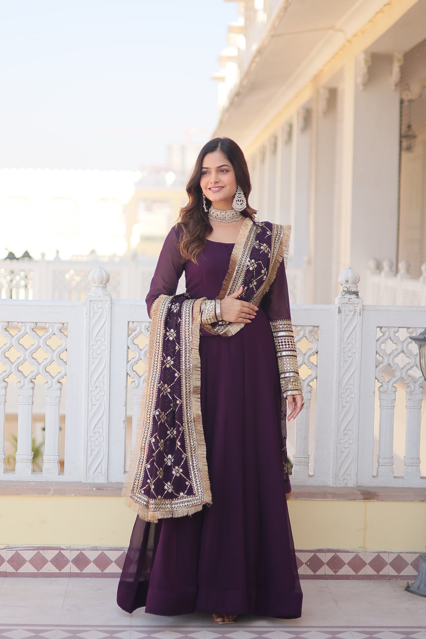 Woman in a purple dress with white patterns standing on a staircase.