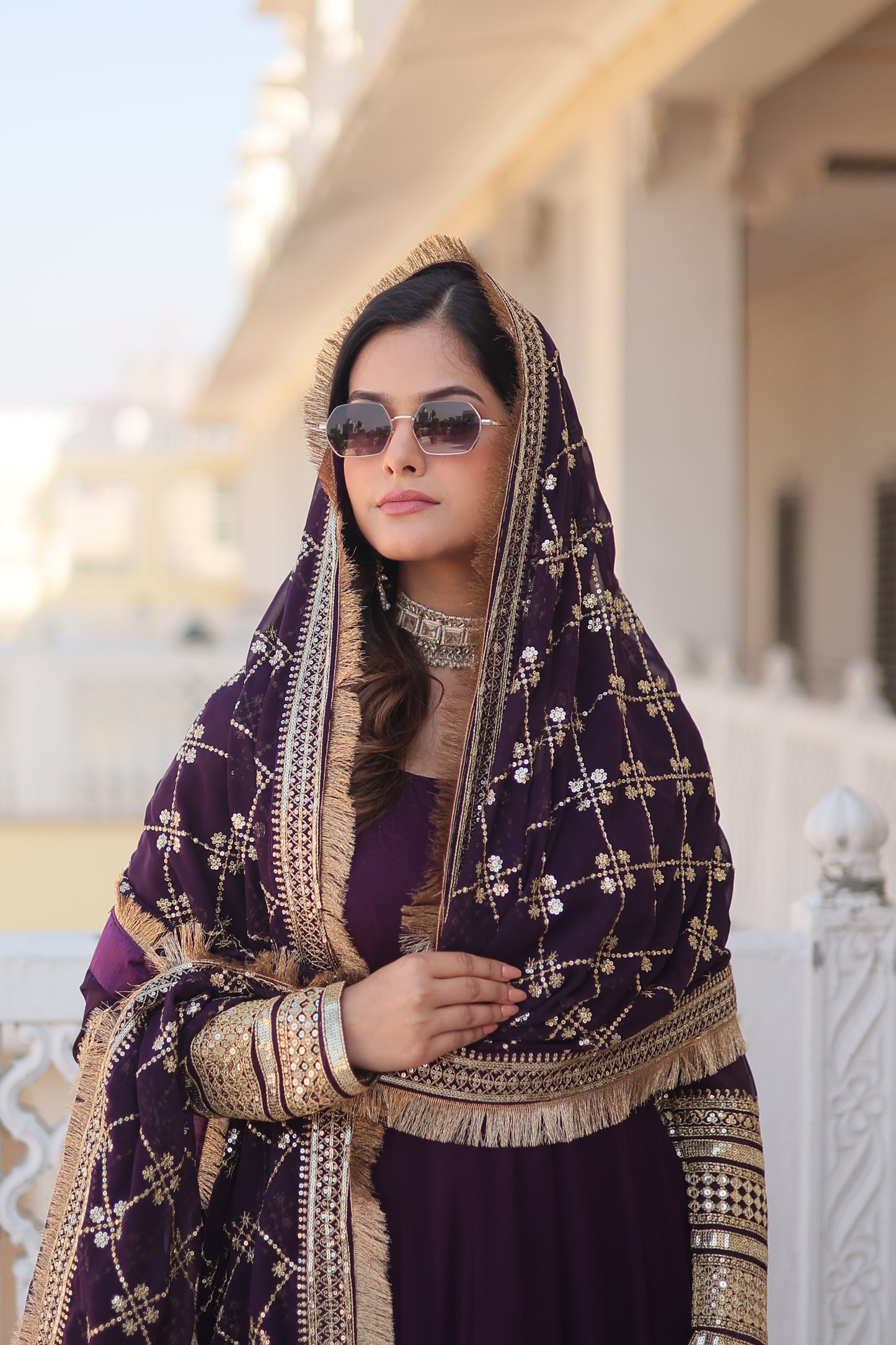 Woman in a traditional embroidered outfit with sunglasses, lying on a white surface.