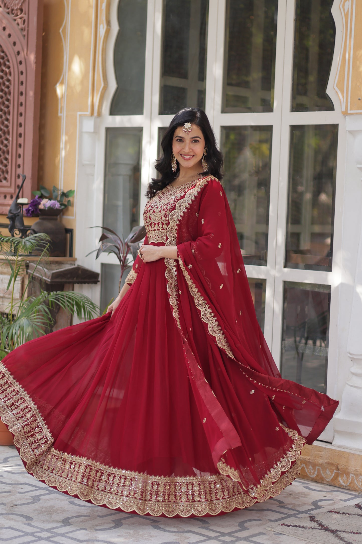 Woman wearing a red traditional outfit with gold embroidery indoors.