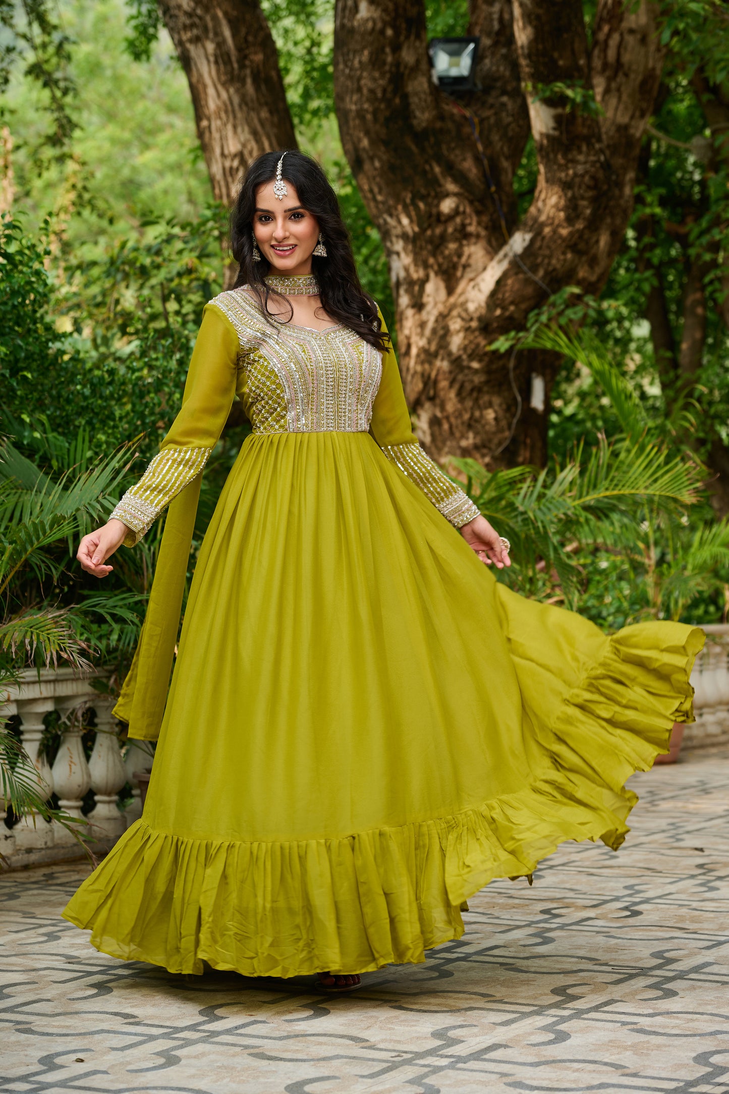Woman in a yellow dress standing outdoors with greenery in the background