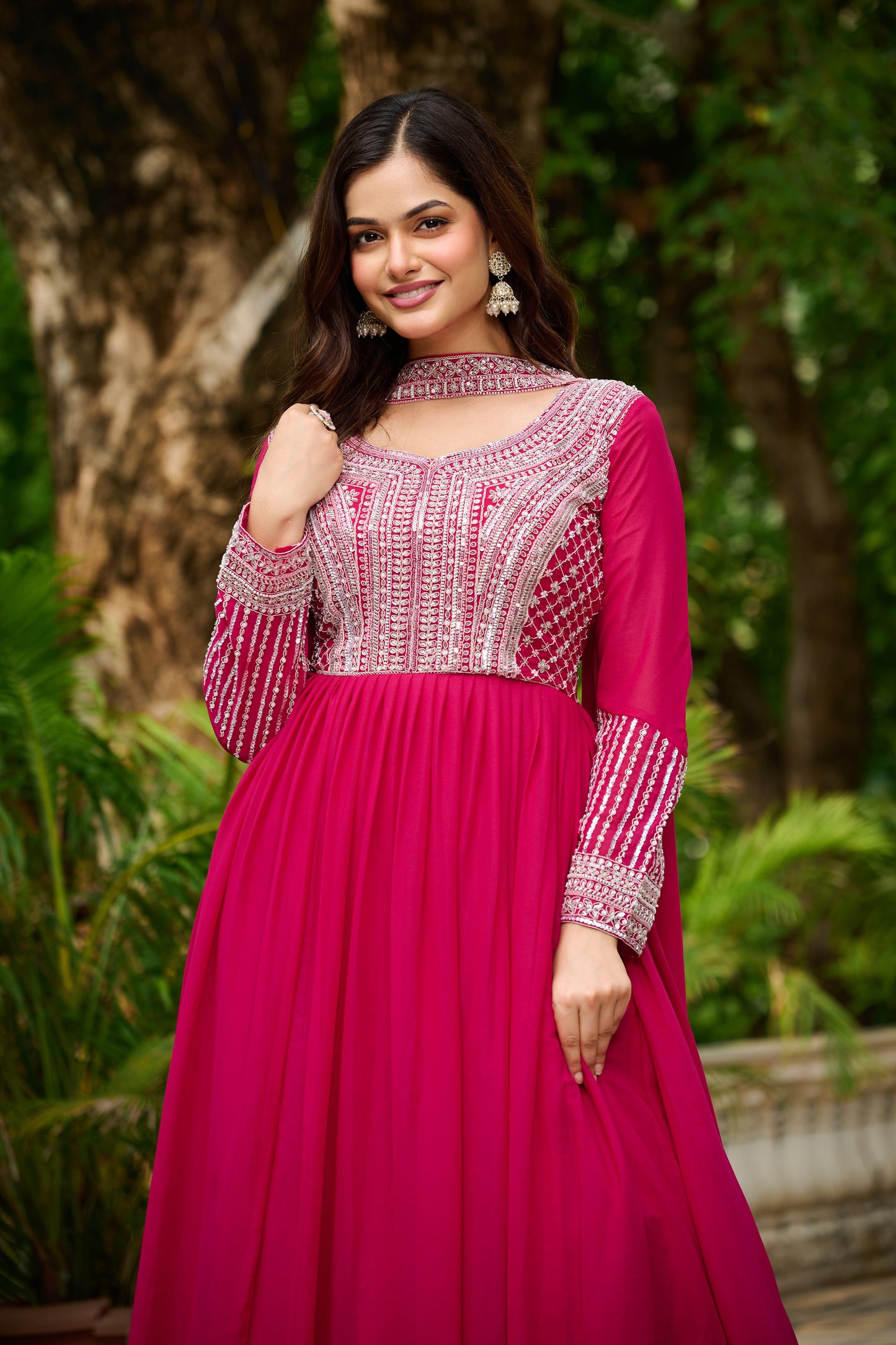 Woman wearing a pink traditional outfit with intricate patterns in a natural setting