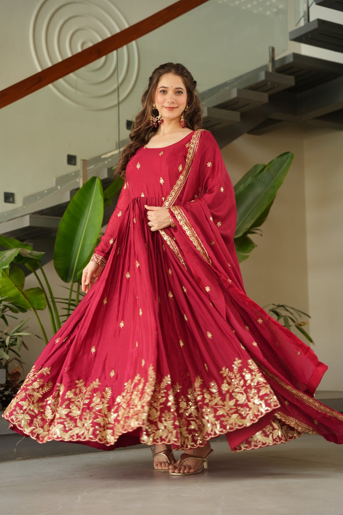 Woman in a red saree with gold details indoors