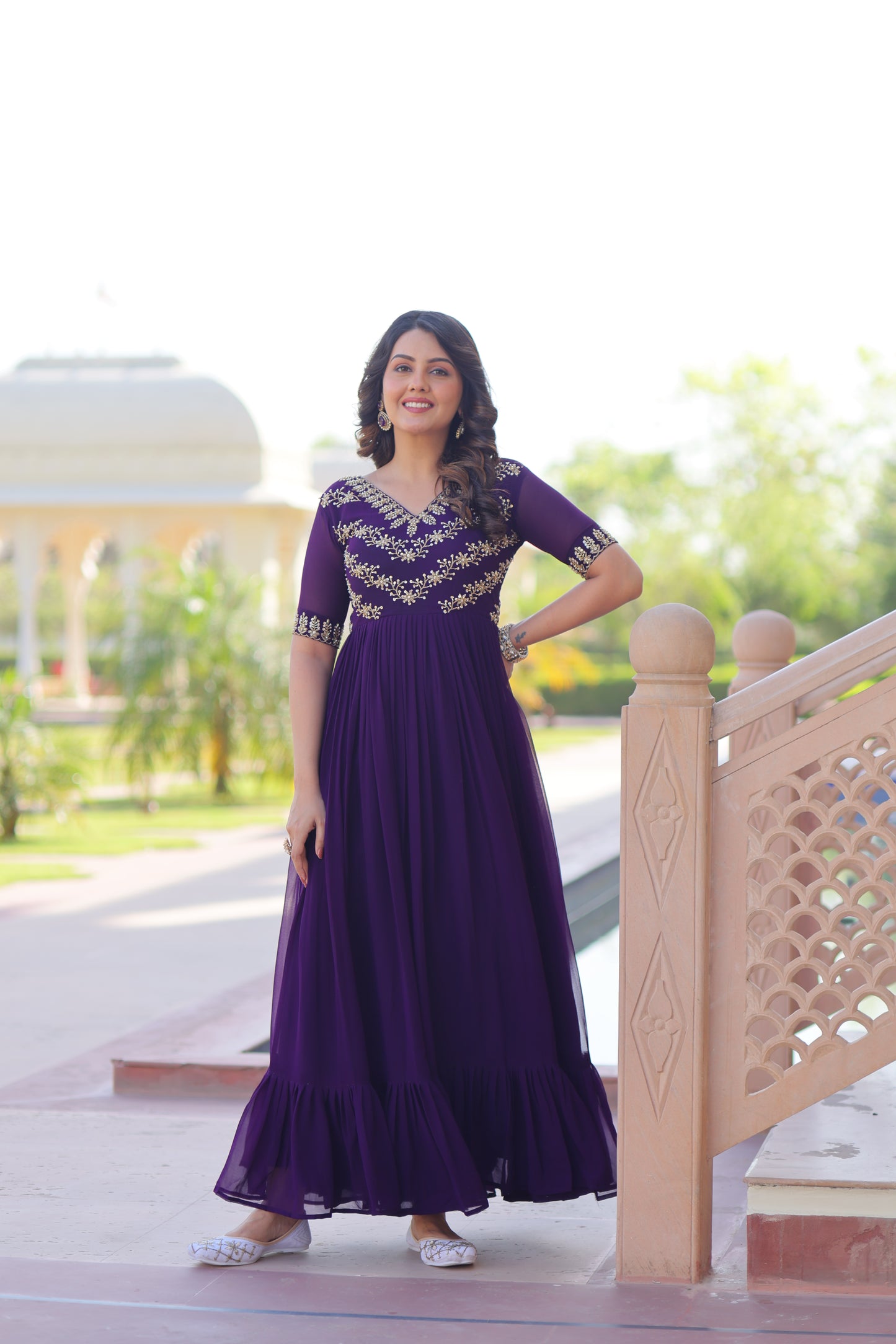 Woman in a purple dress standing on a wooden bench with a blurred outdoor background