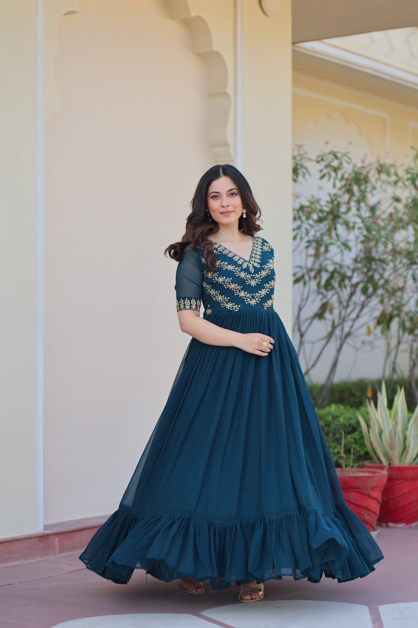 Woman in a long dark green dress standing outdoors with a blurred background