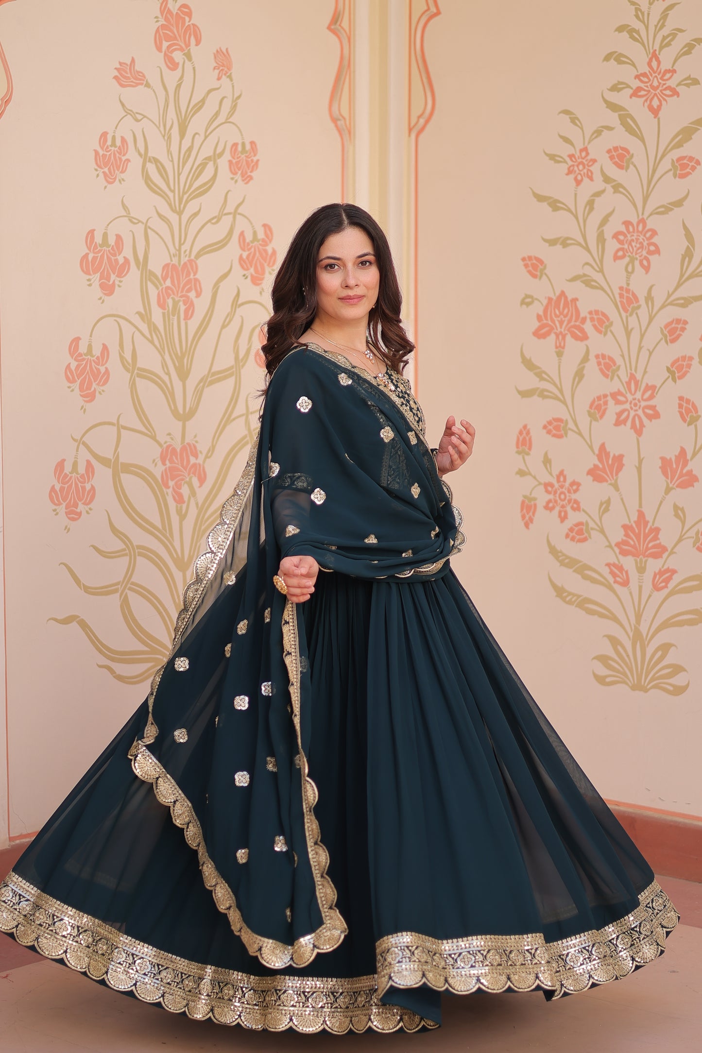 Woman wearing a dark blue dress with intricate white patterns against a floral background