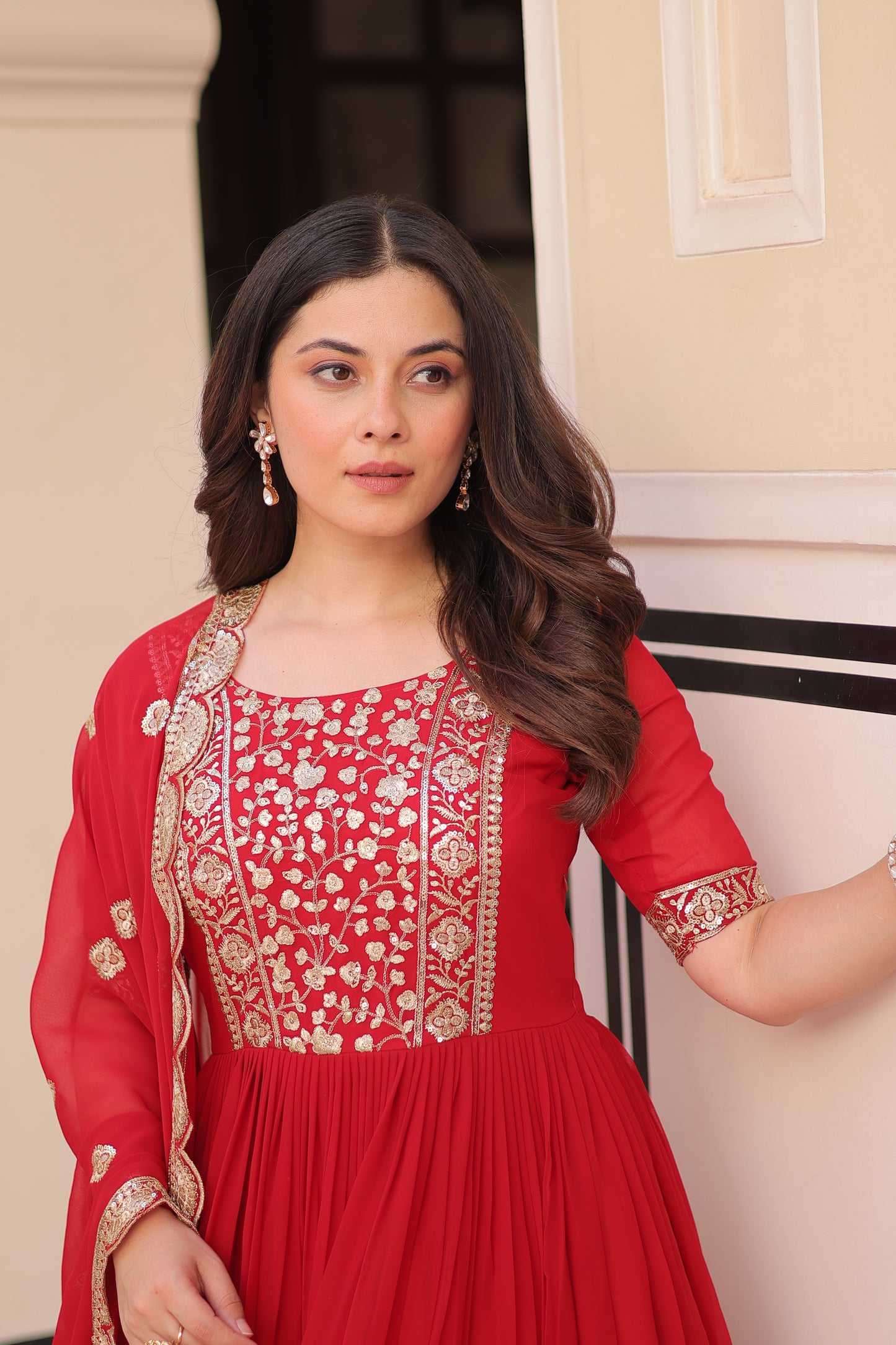 Woman wearing a red traditional outfit with gold embroidery.
