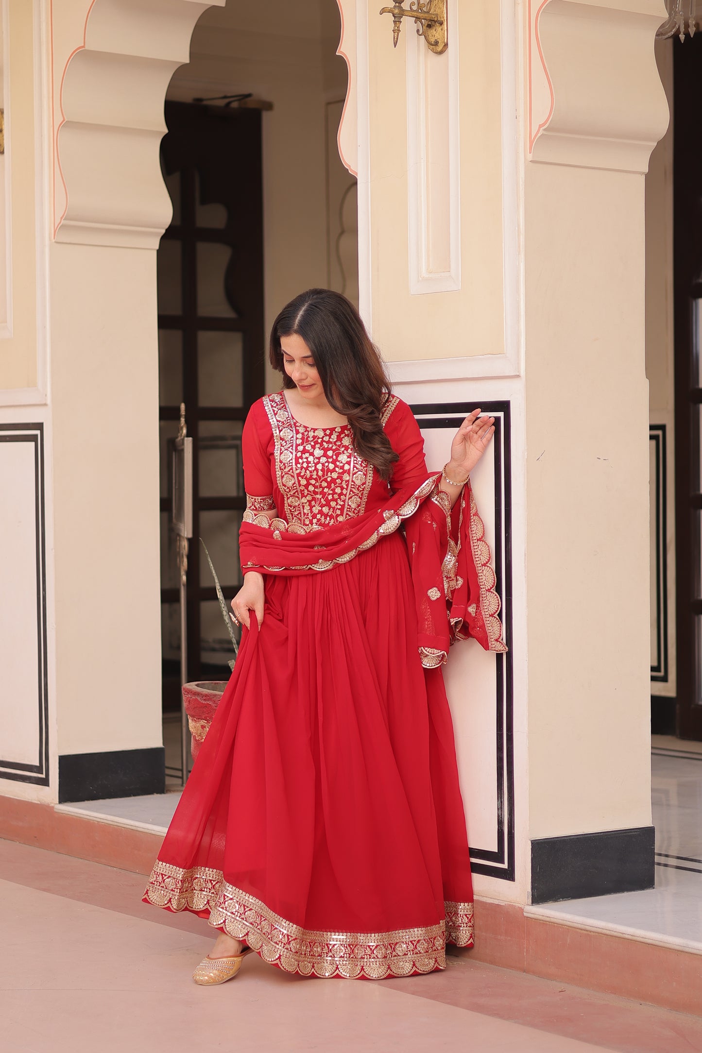 Woman in a red traditional outfit standing in front of a mirror.