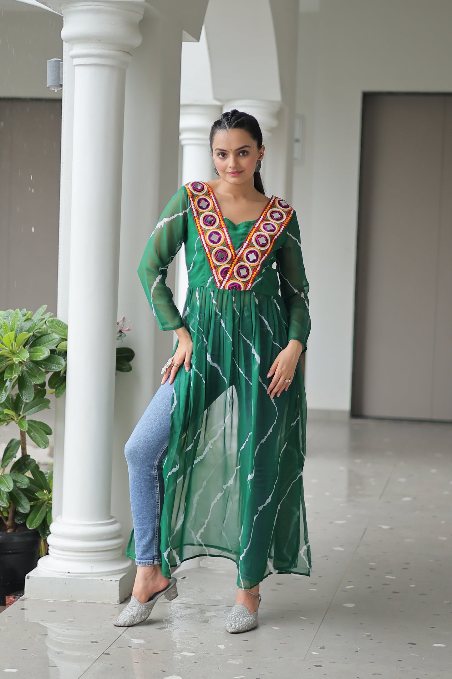 Woman wearing a green dress with a colorful pattern standing in front of a white column.