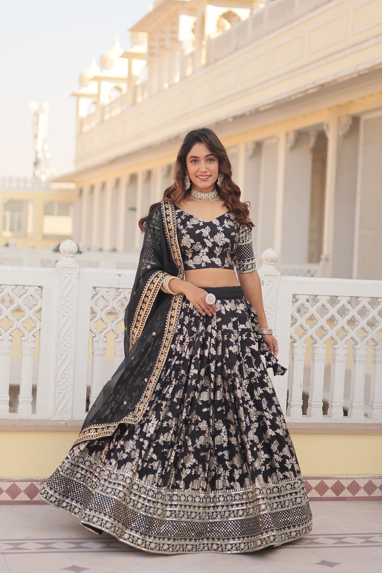 Woman in a black and white patterned traditional outfit standing in front of a white lattice background.