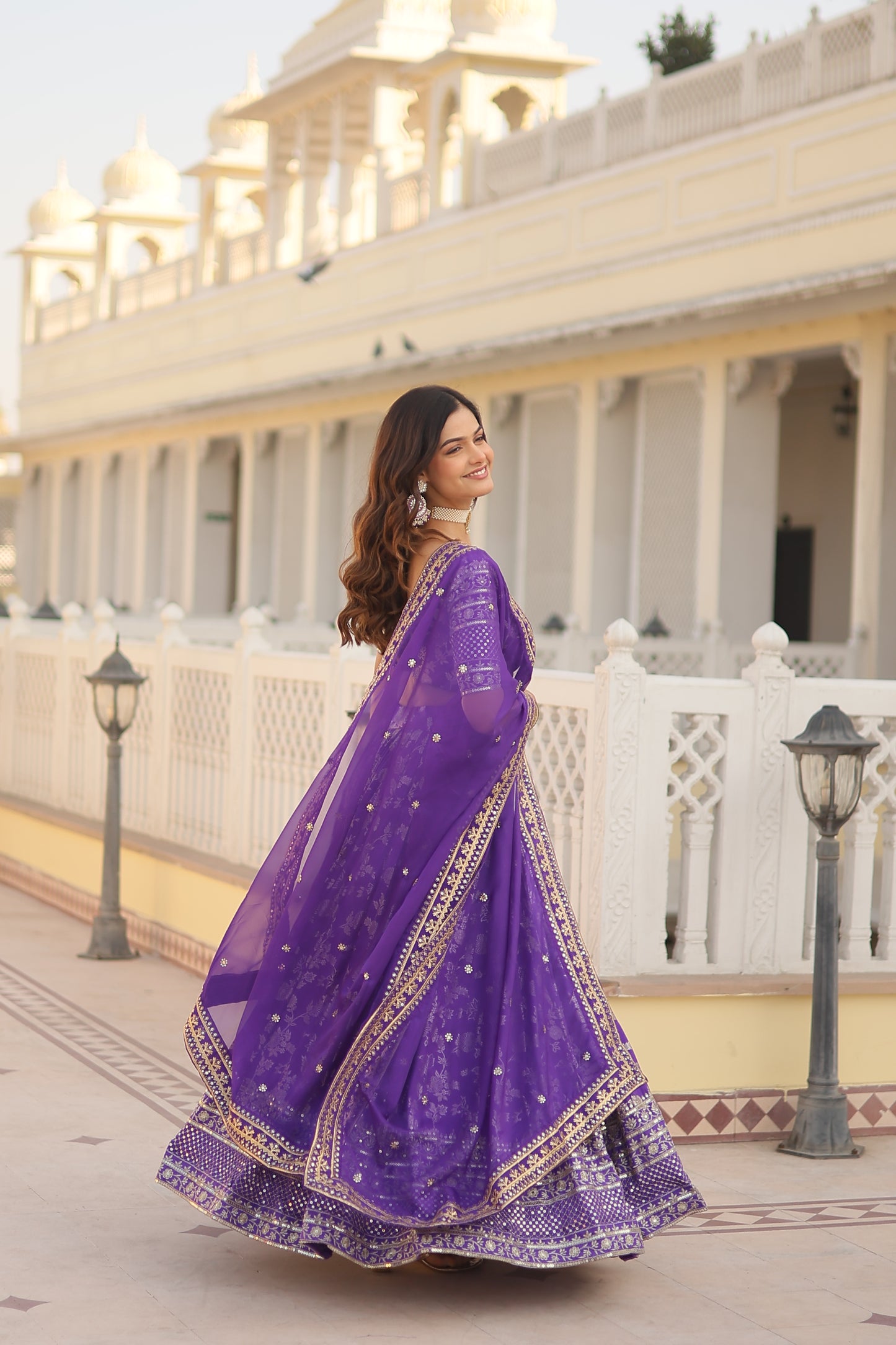Woman wearing a purple saree with a white building in the background