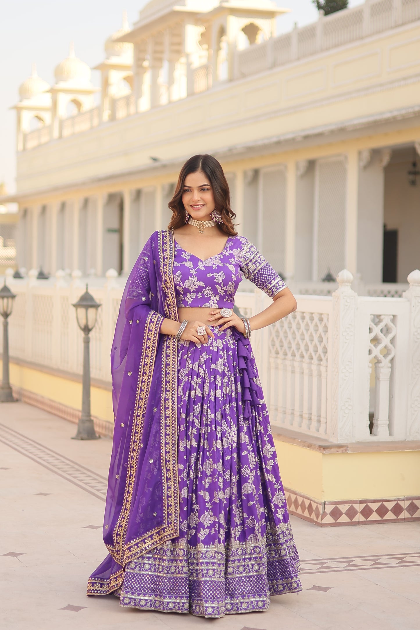 Woman in a purple traditional outfit standing in a staircase.