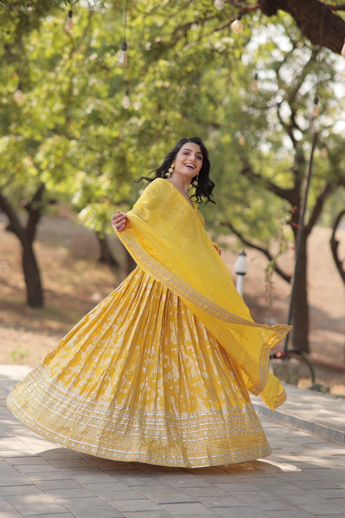 Woman in a yellow dress standing outdoors with trees in the background