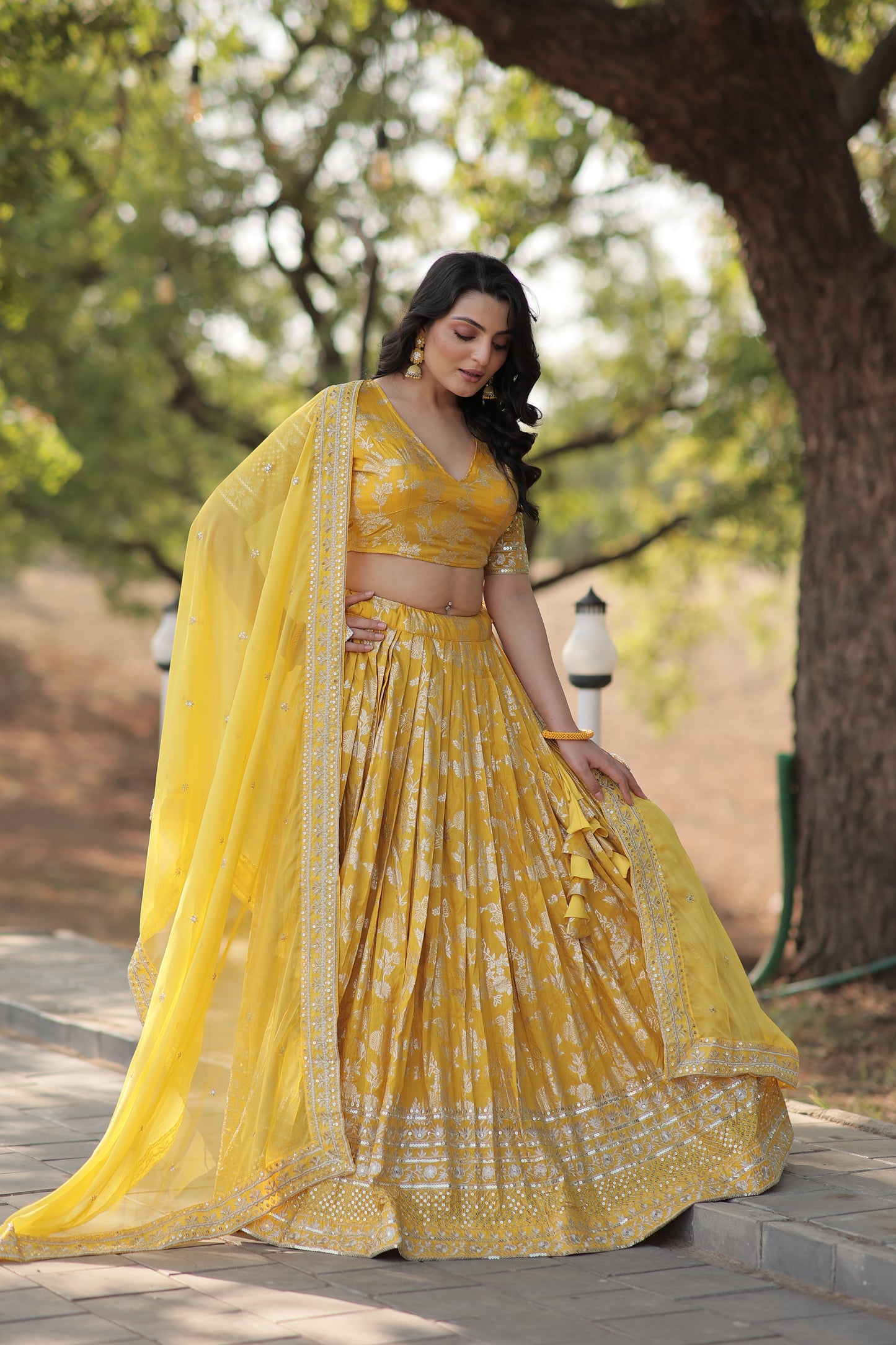 Woman in a yellow dress standing outdoors with trees in the background