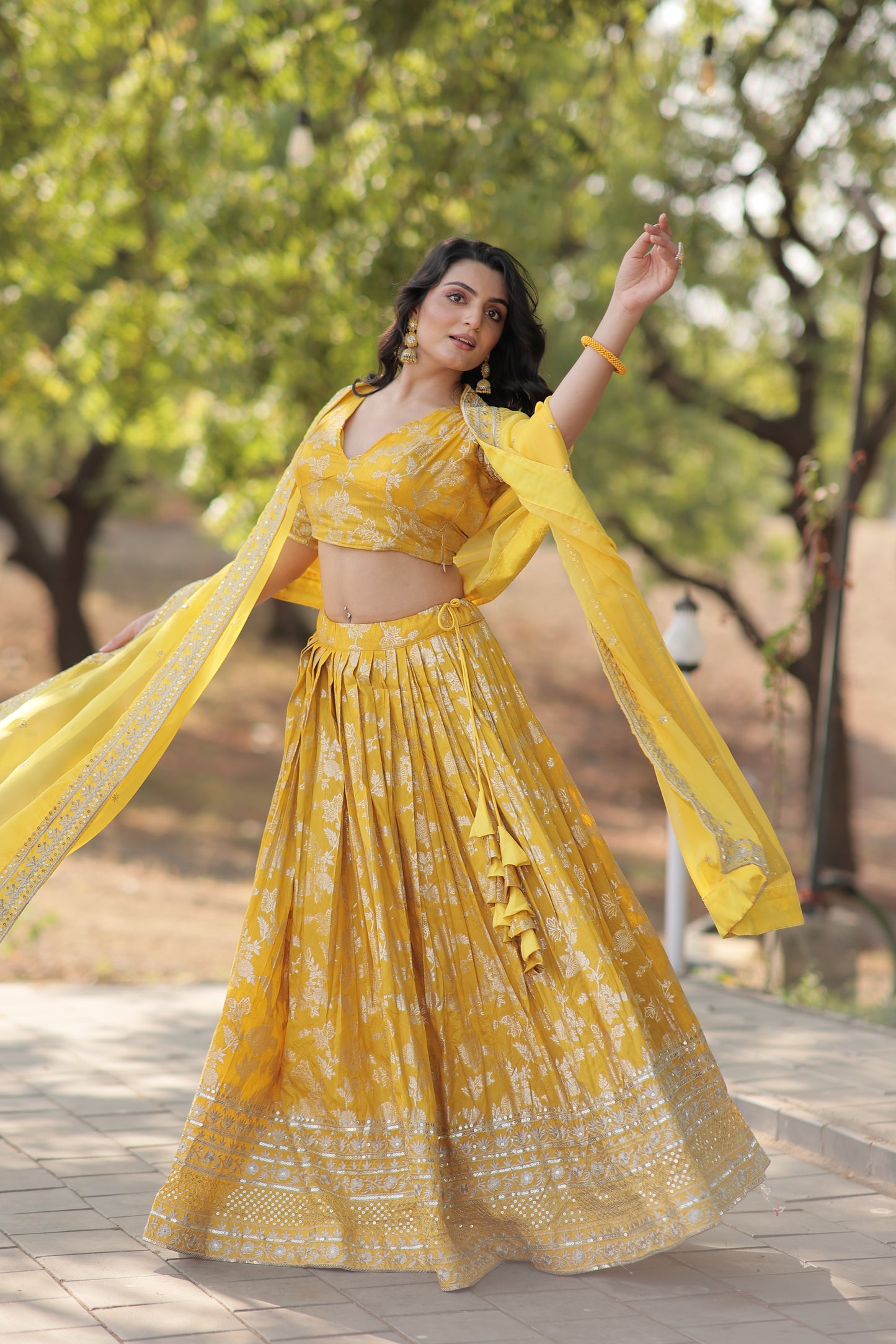 Woman in a yellow dress standing outdoors with trees in the background