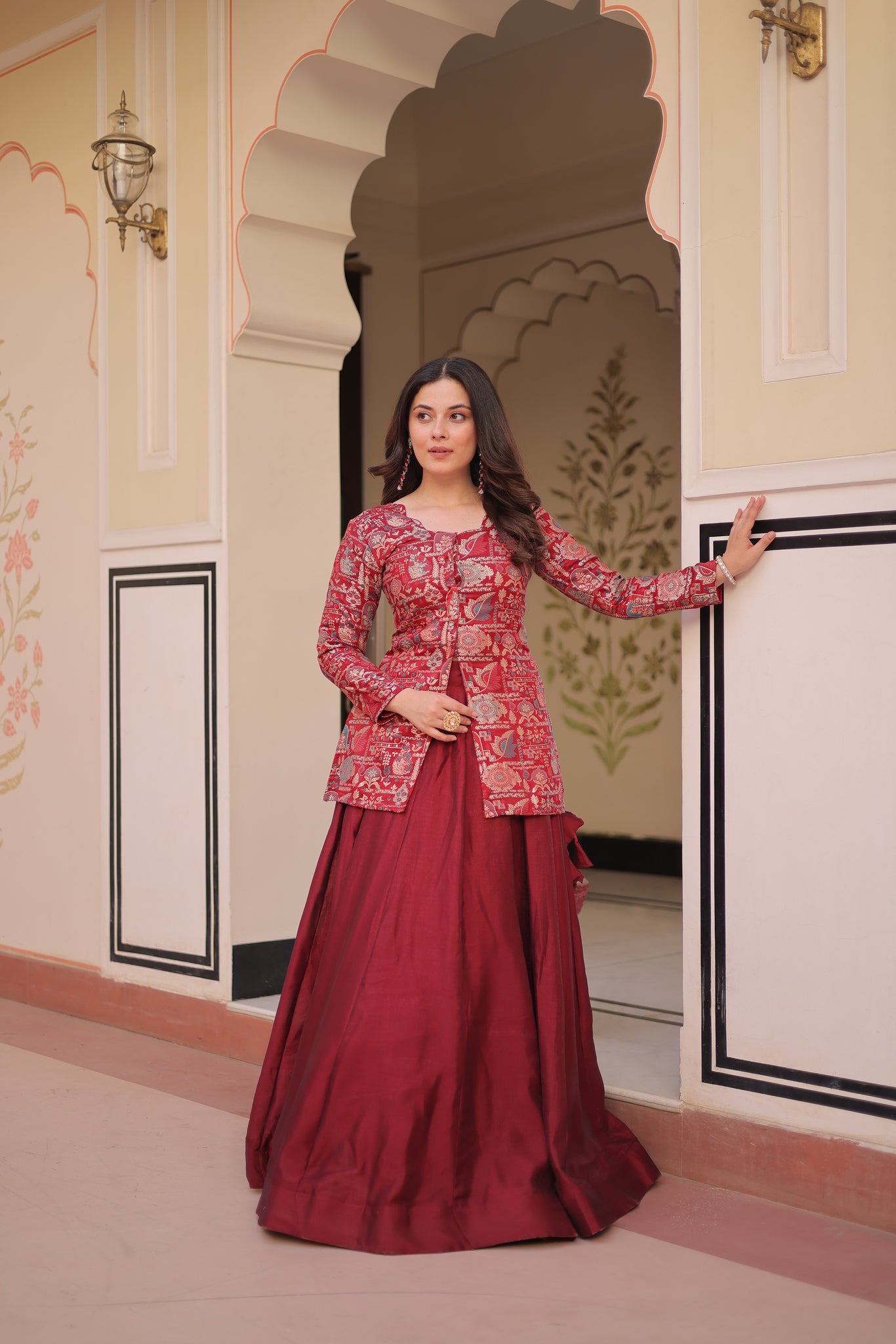 Woman in a red dress with floral patterns standing in front of a decorative door.
