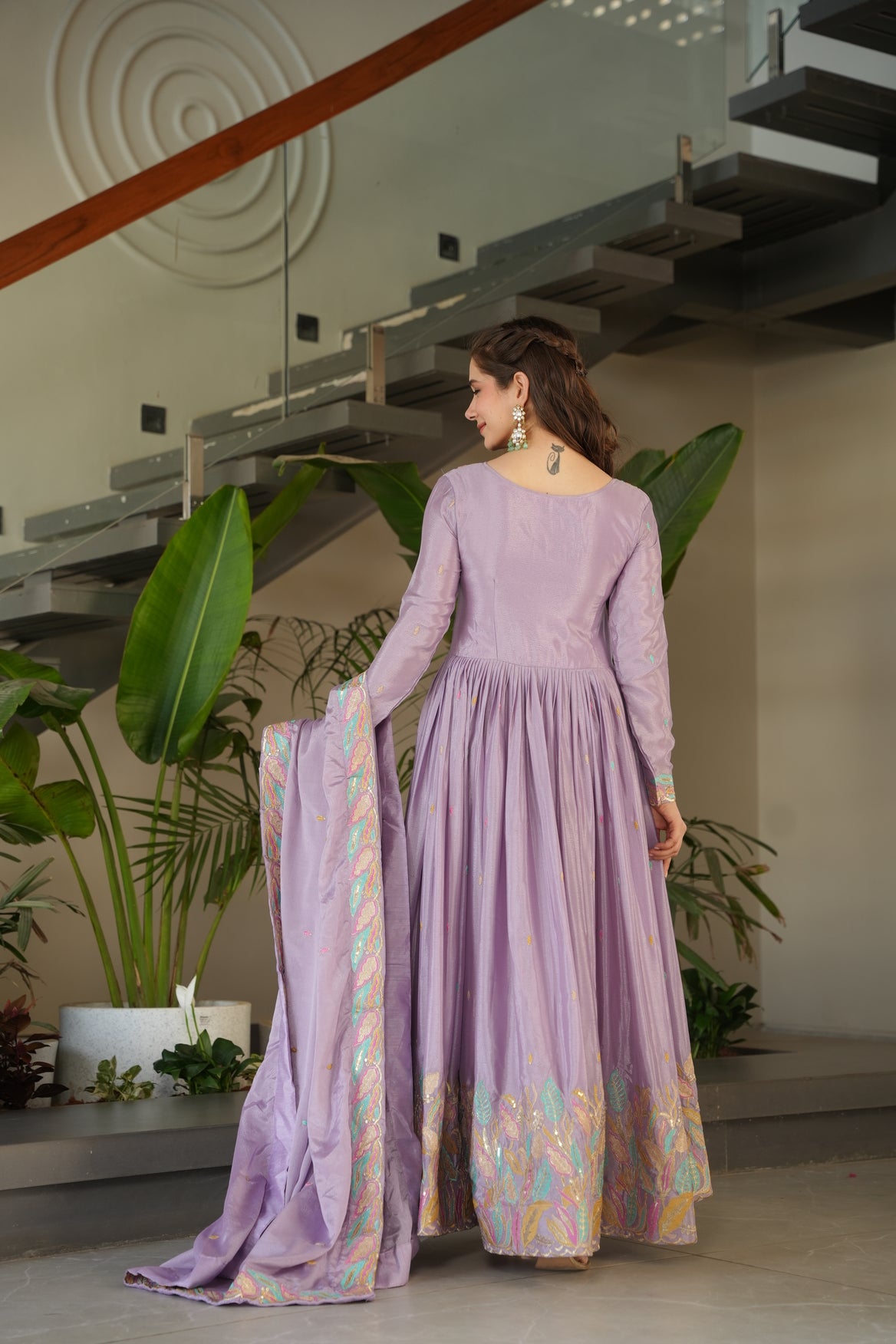 Mannequin wearing a long purple dress with floral patterns in an indoor setting.