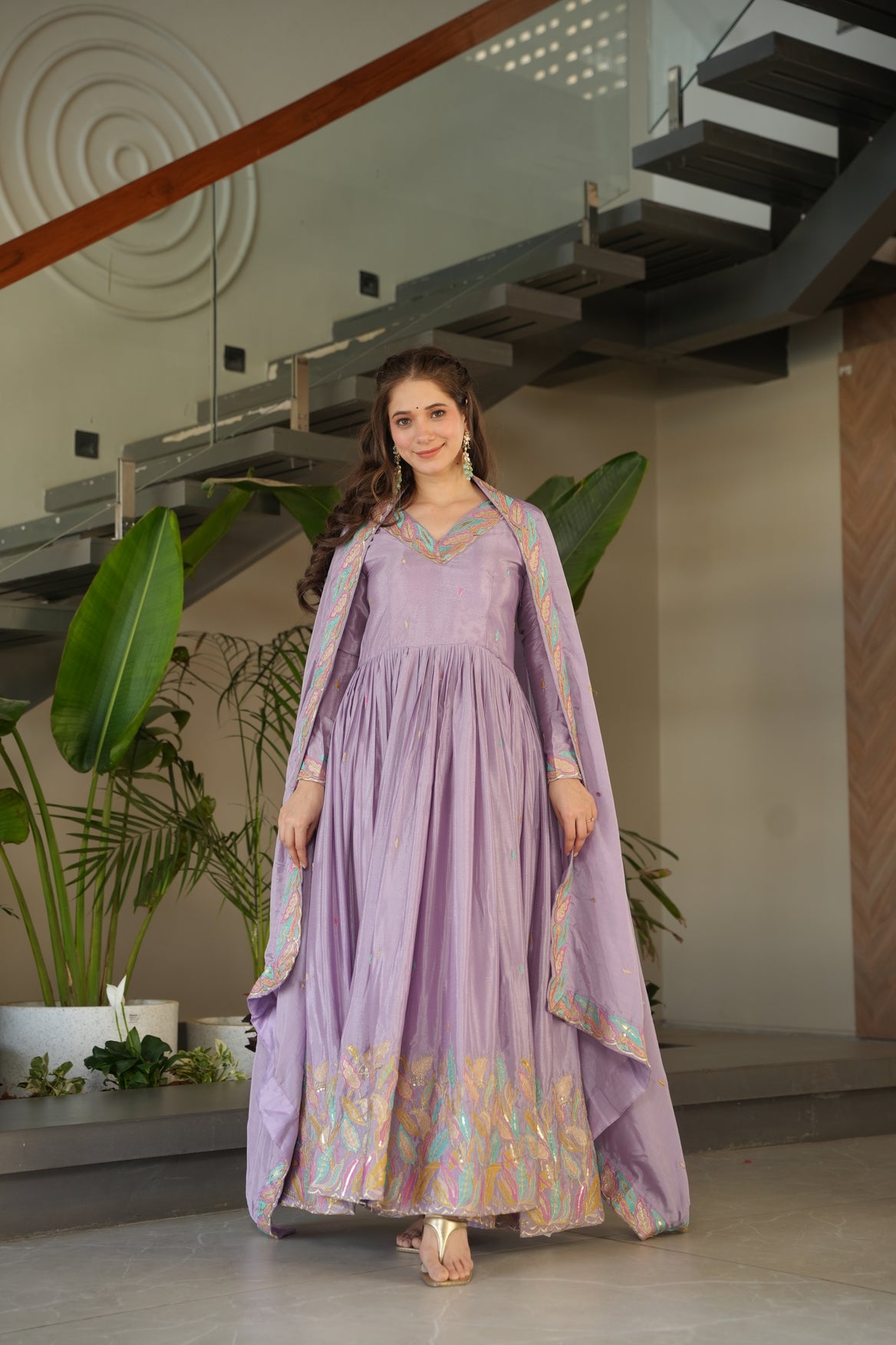 Woman in a purple dress standing indoors with plants in the background