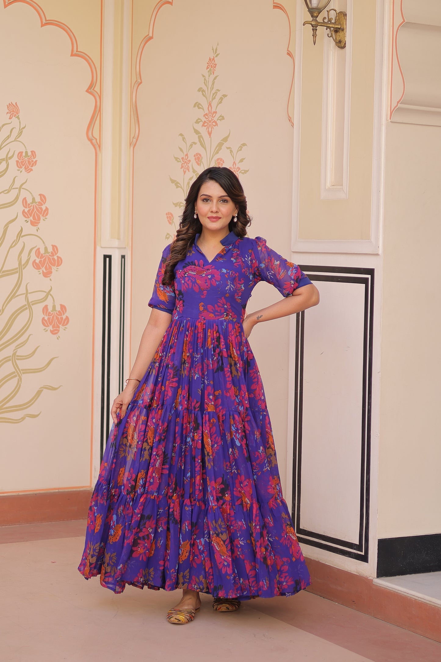 Woman in a blue floral dress standing in a room with decorative elements.