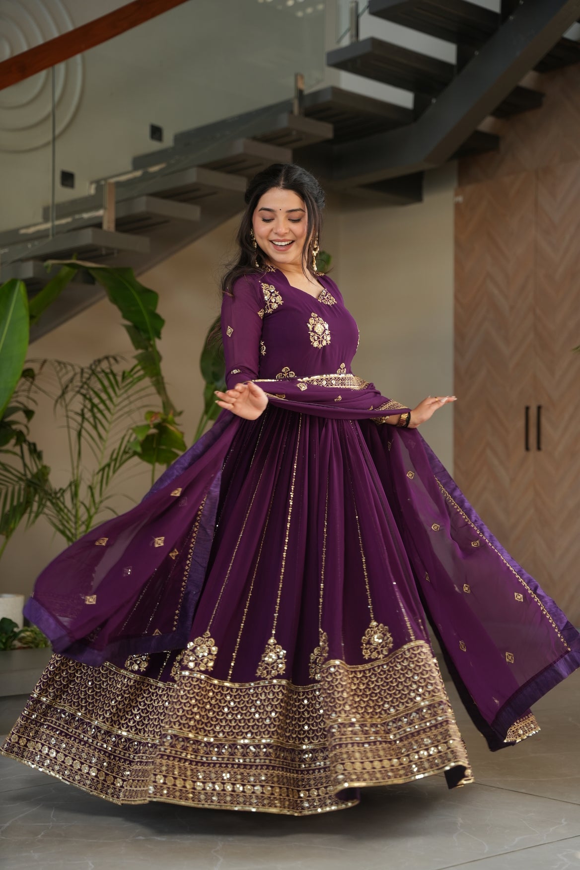 Woman in a purple traditional outfit with gold details indoors.