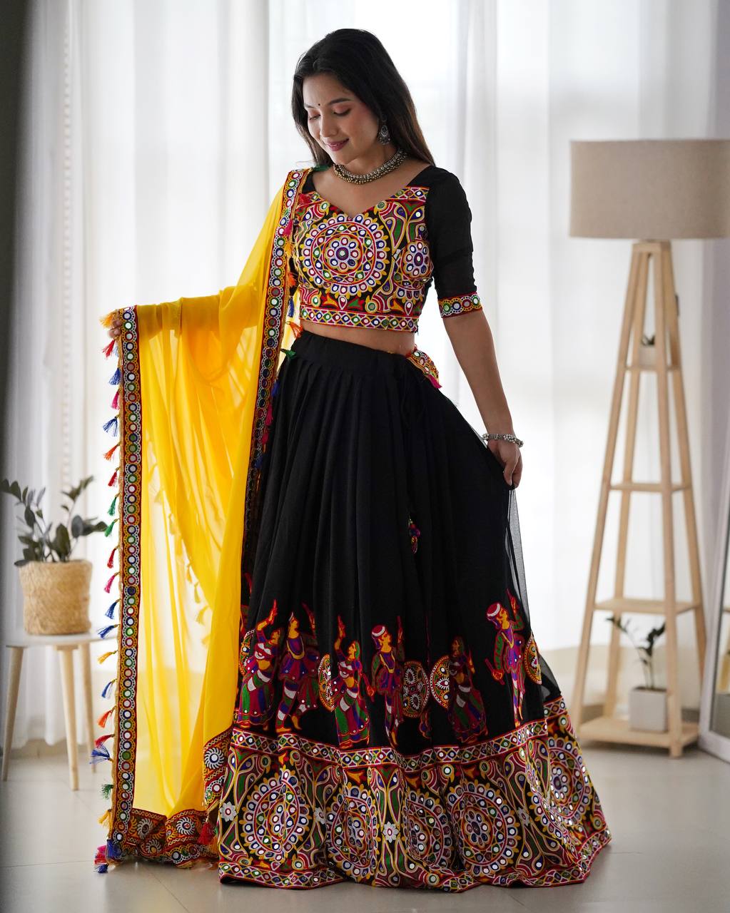 Woman wearing a traditional black and yellow outfit with intricate patterns indoors.