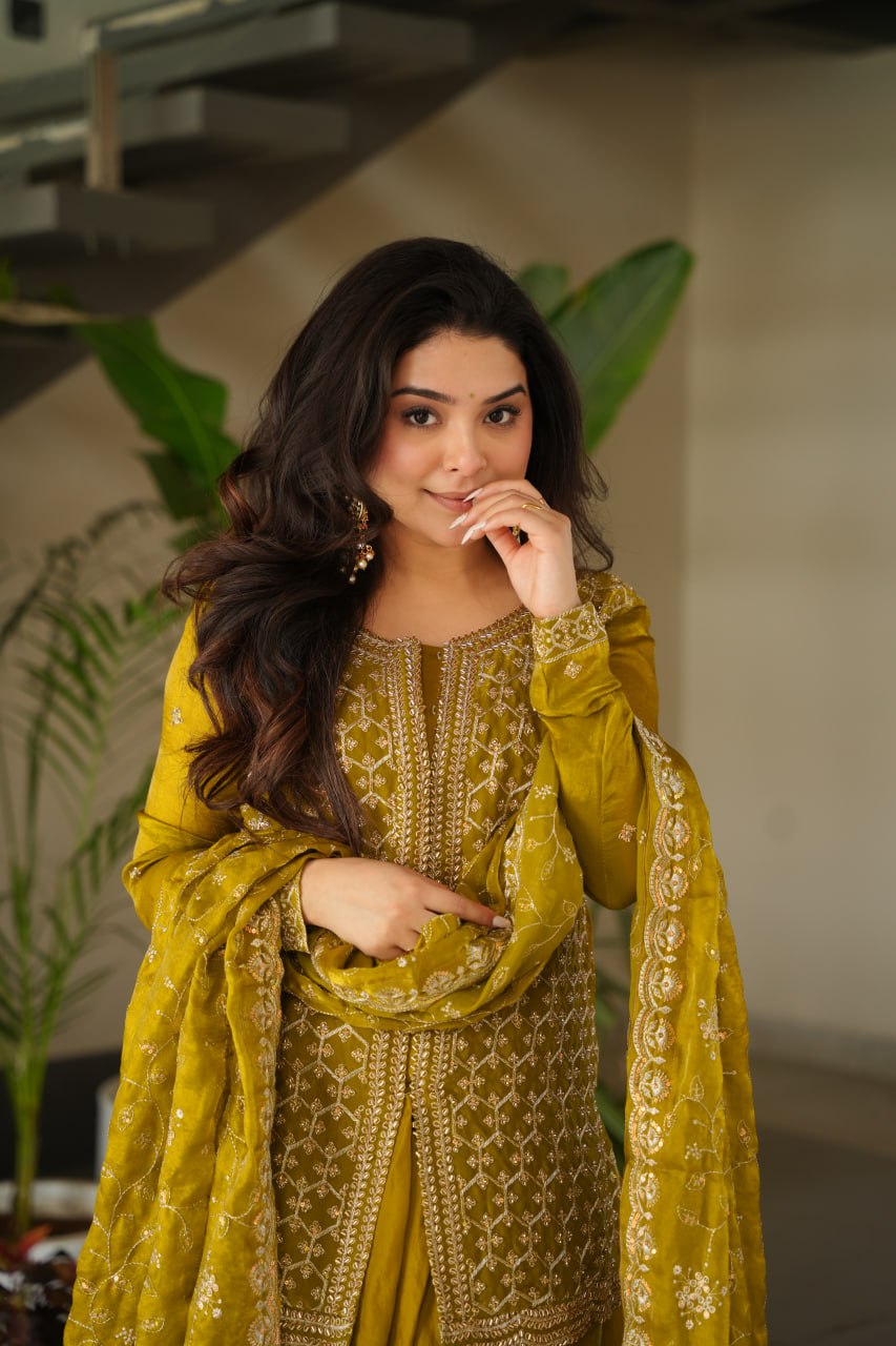 Woman in a yellow traditional outfit with intricate patterns indoors.