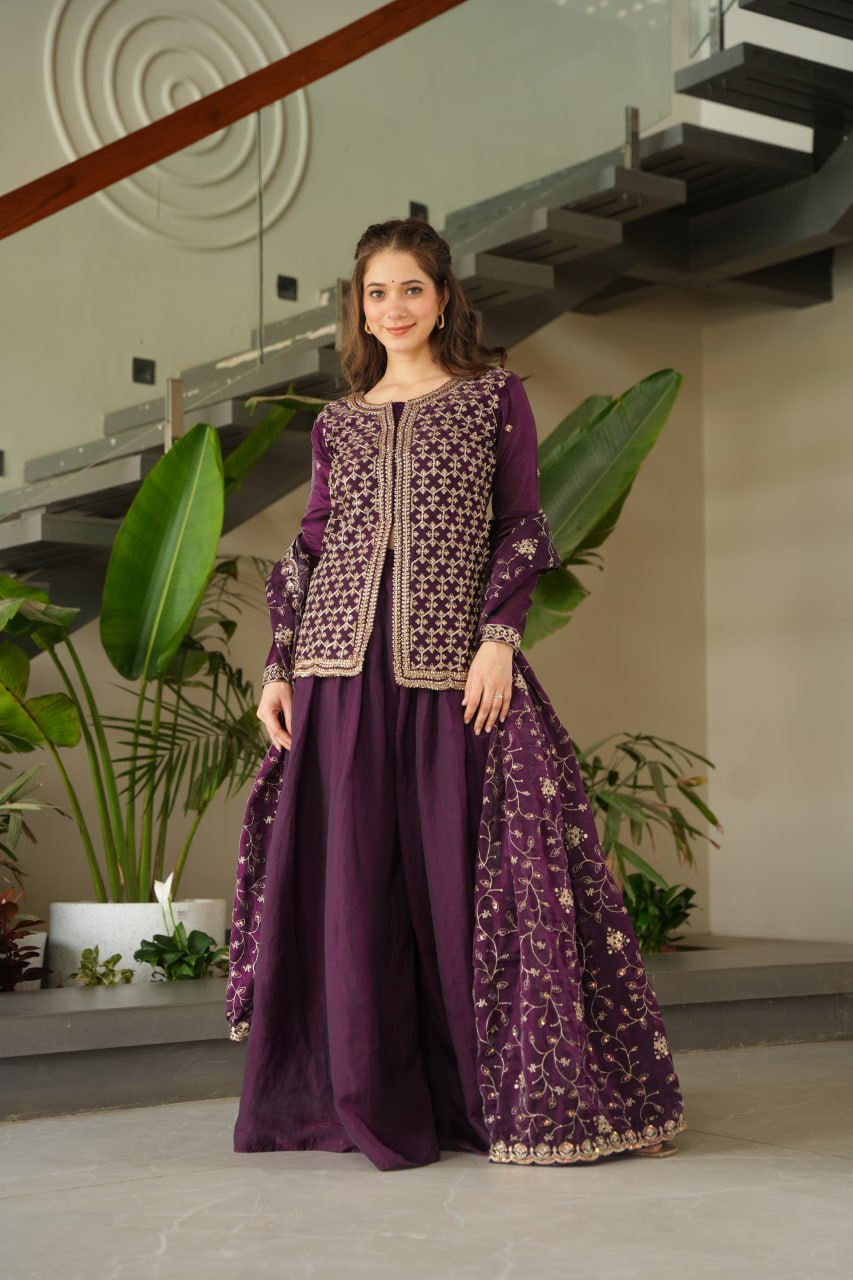 Woman wearing a purple traditional outfit with intricate patterns in an indoor setting.