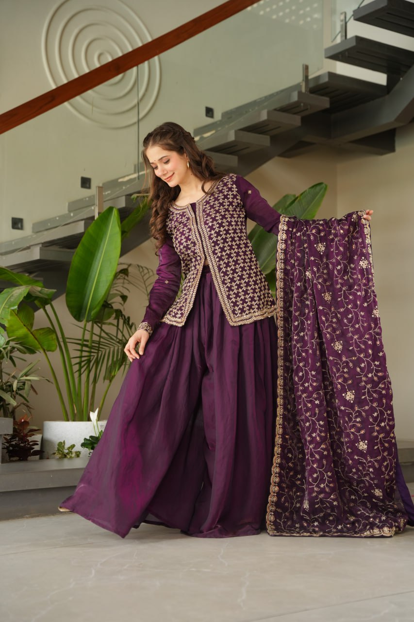 Woman in a purple traditional outfit with a matching dupatta in a modern indoor setting.