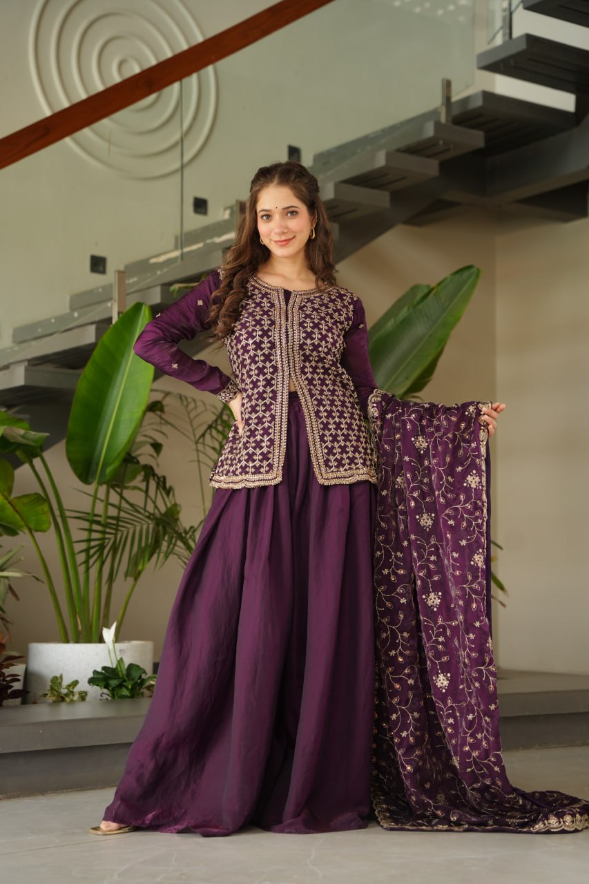 Woman in a purple traditional outfit with floral patterns indoors.
