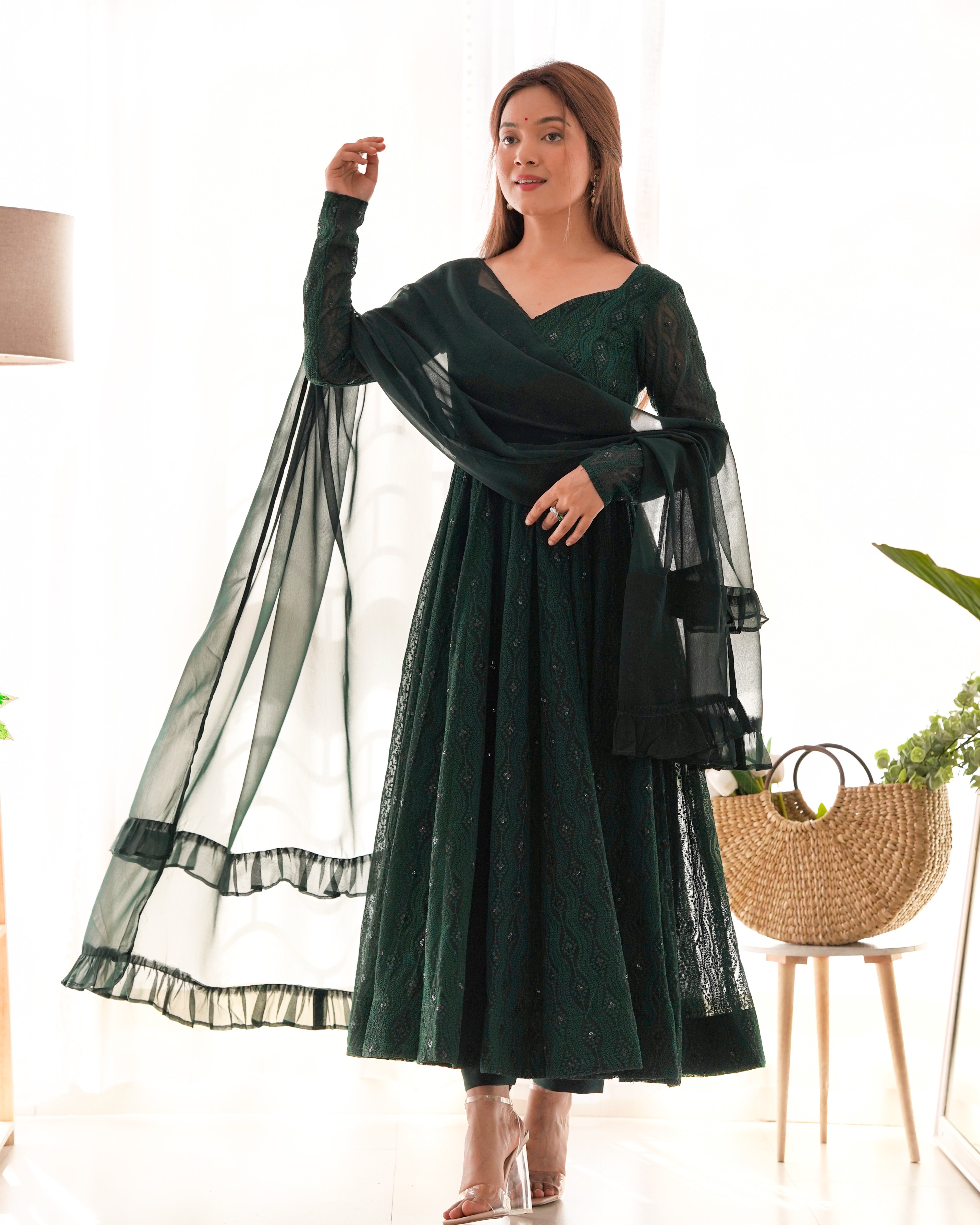Woman wearing a dark green dress with sheer sleeves indoors.