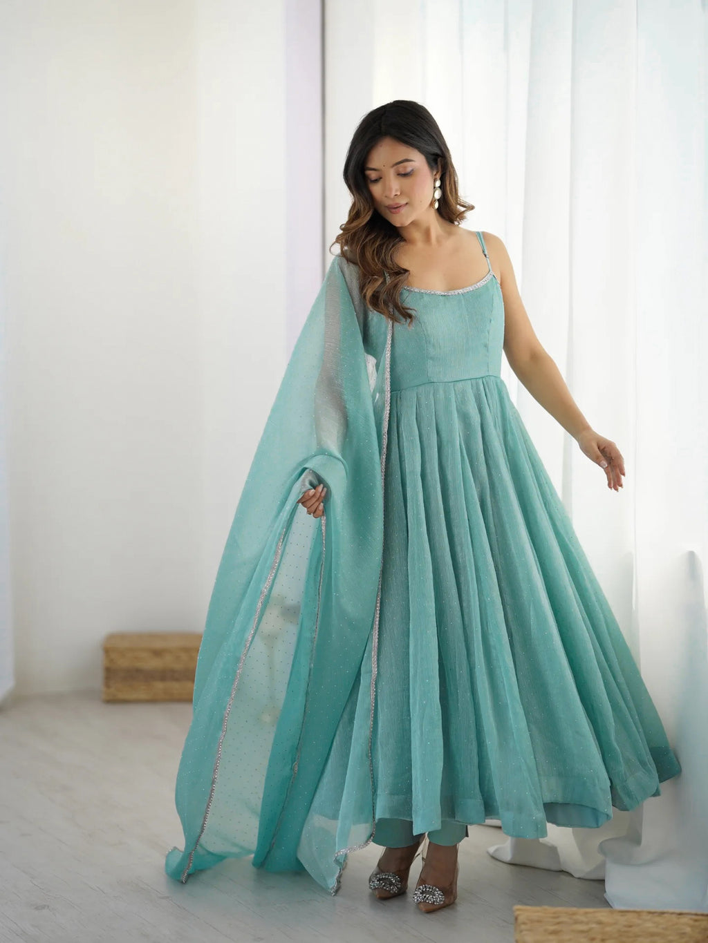 Woman wearing a light blue dress with a matching dupatta in a minimalistic setting