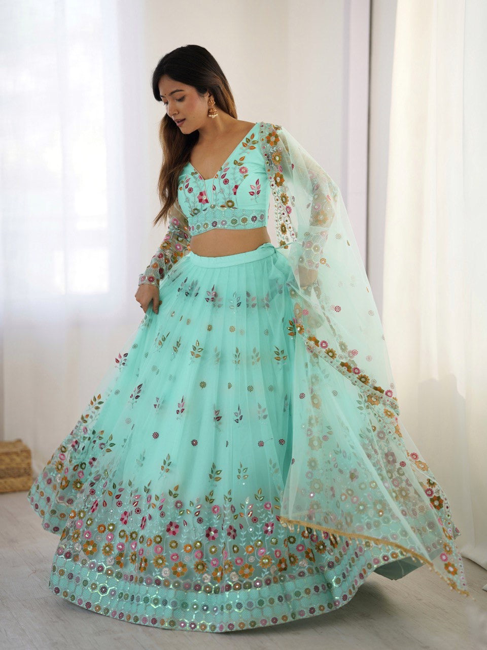 Woman wearing a light blue embroidered traditional outfit with a white background