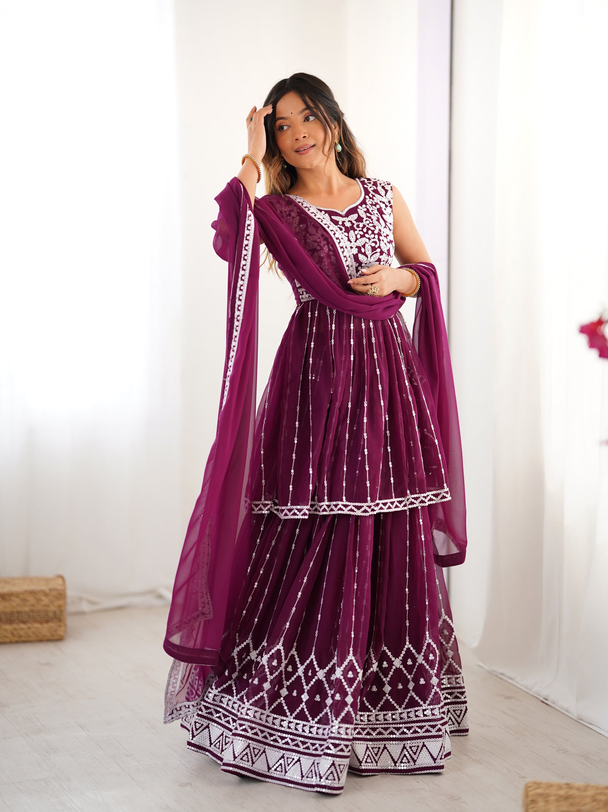 Woman wearing a purple traditional outfit with white patterns in a minimalistic setting