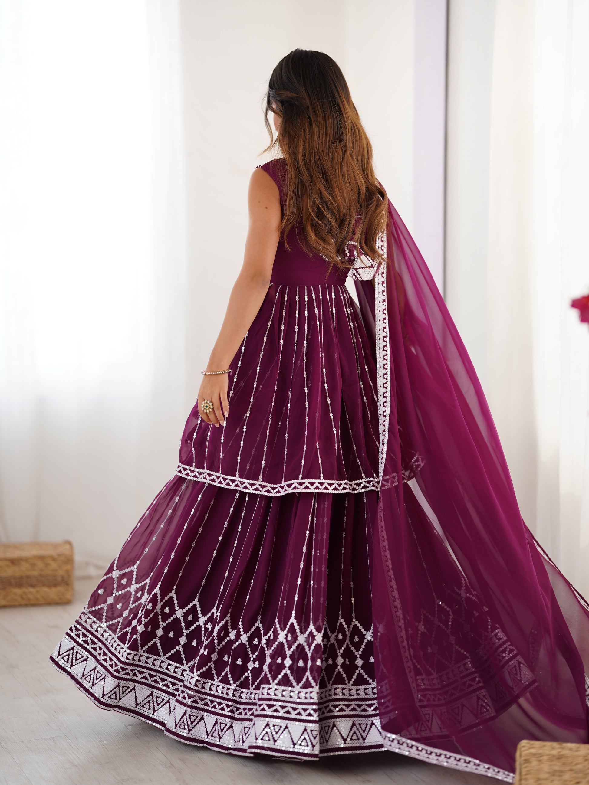 Woman wearing a purple traditional outfit with white patterns indoors.