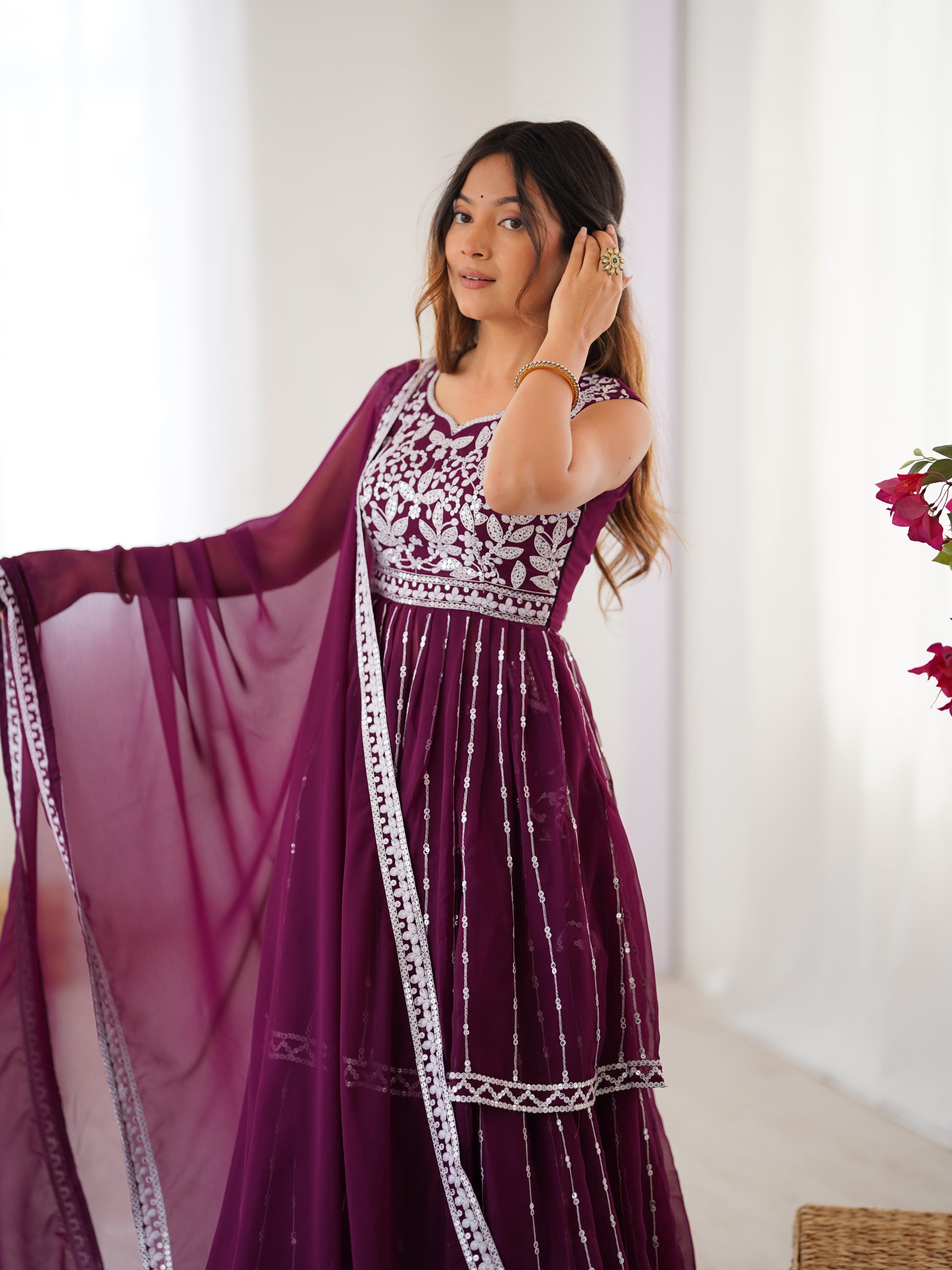 Woman wearing a purple dress with white patterns in a room.