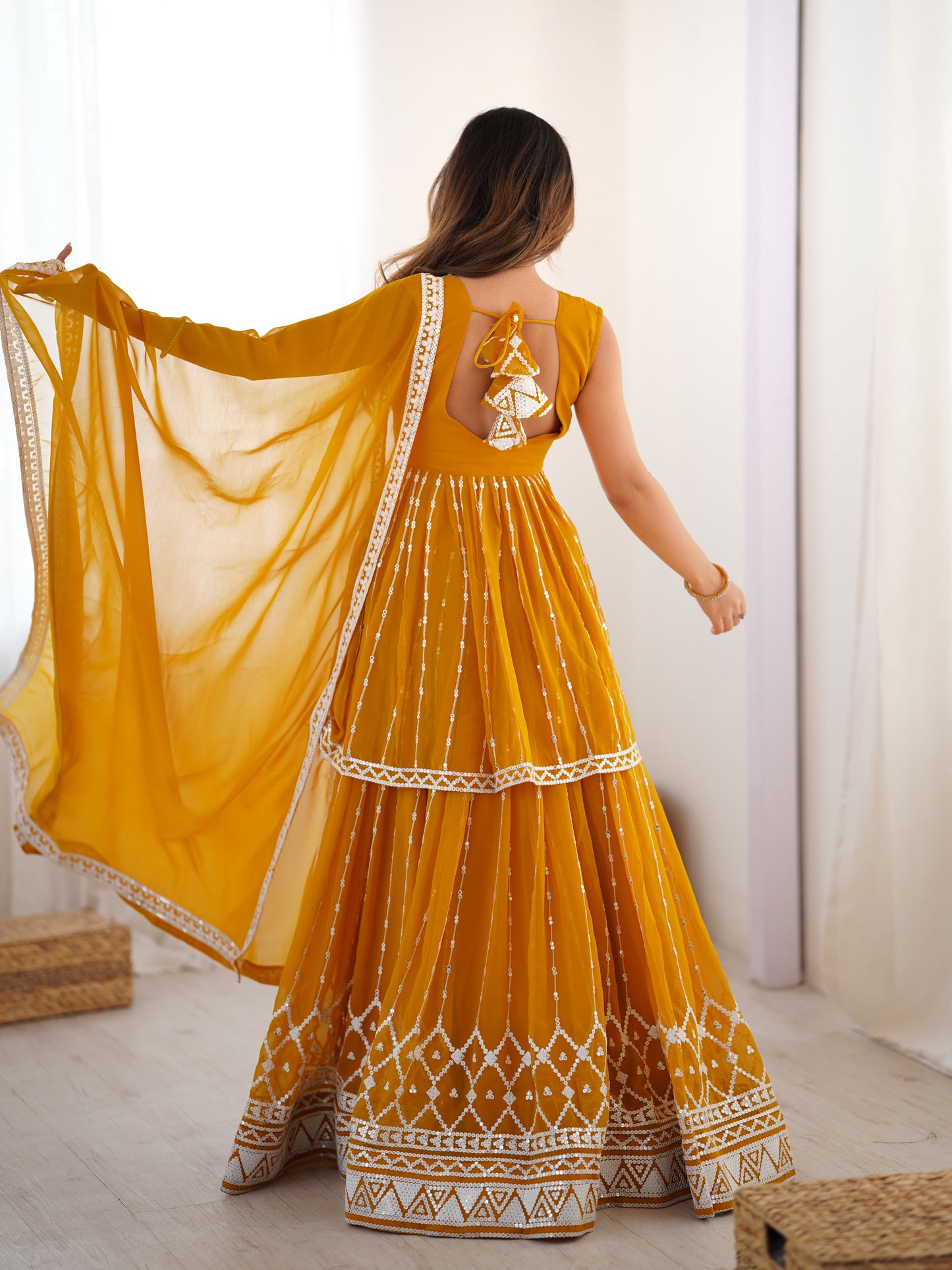 Woman wearing a yellow traditional dress with a white pattern indoors.