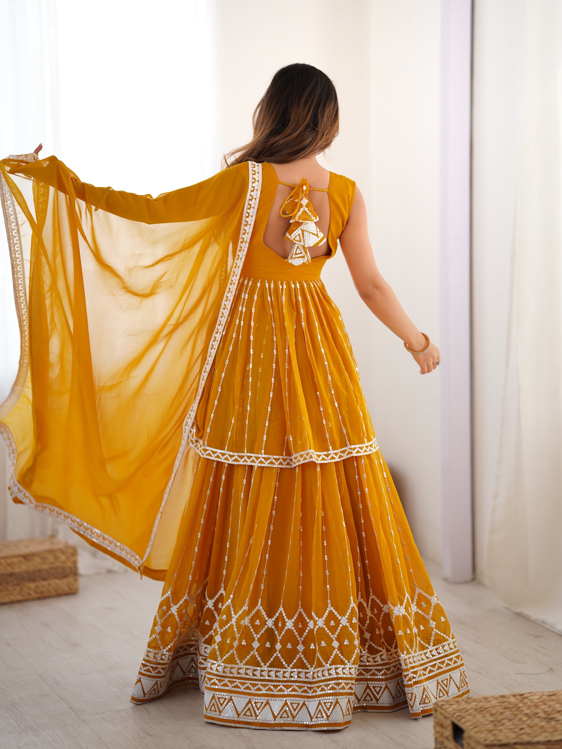 Woman wearing a yellow traditional dress with a white pattern indoors.