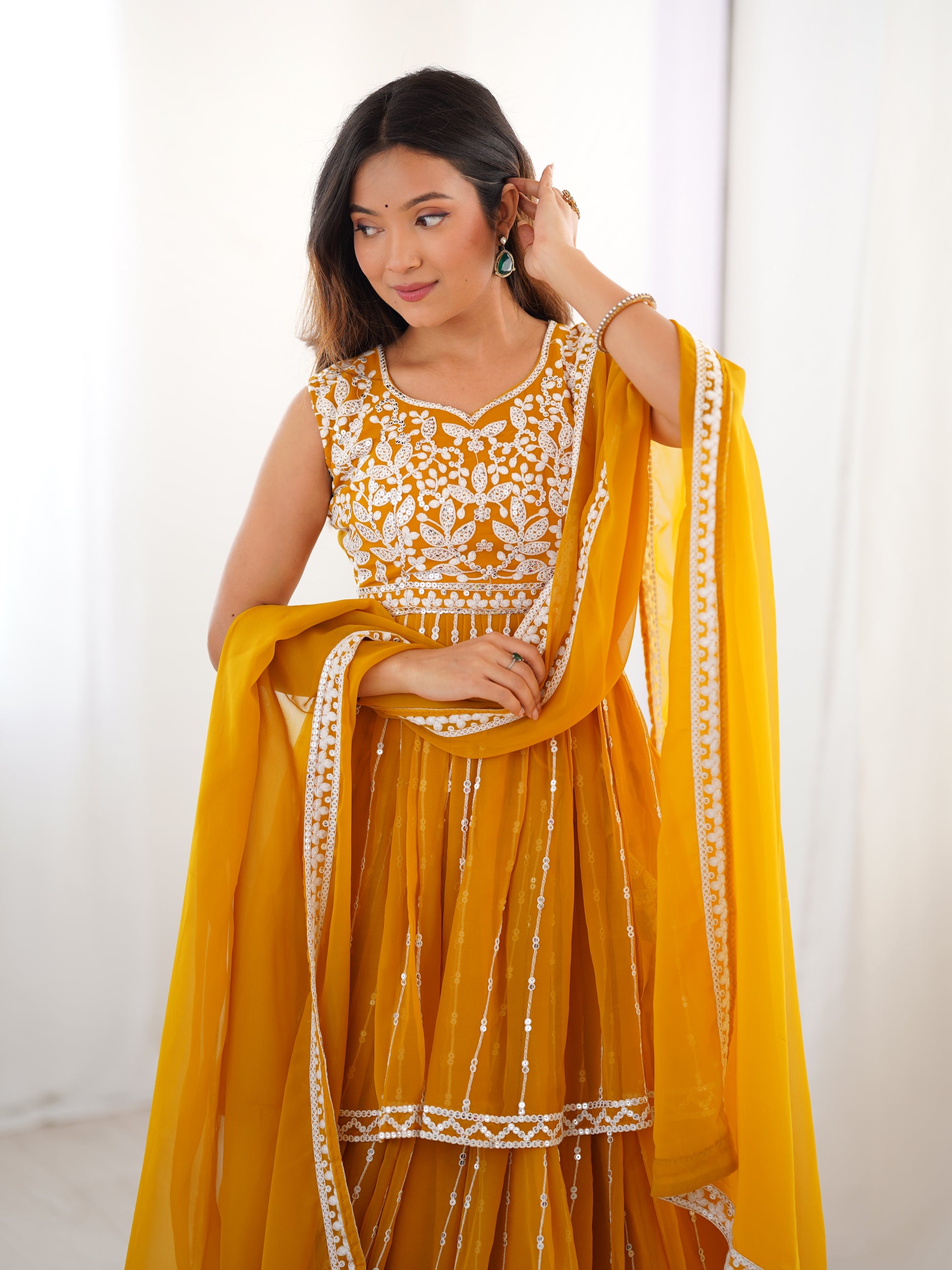 Woman wearing a yellow traditional outfit with white embroidery against a white background